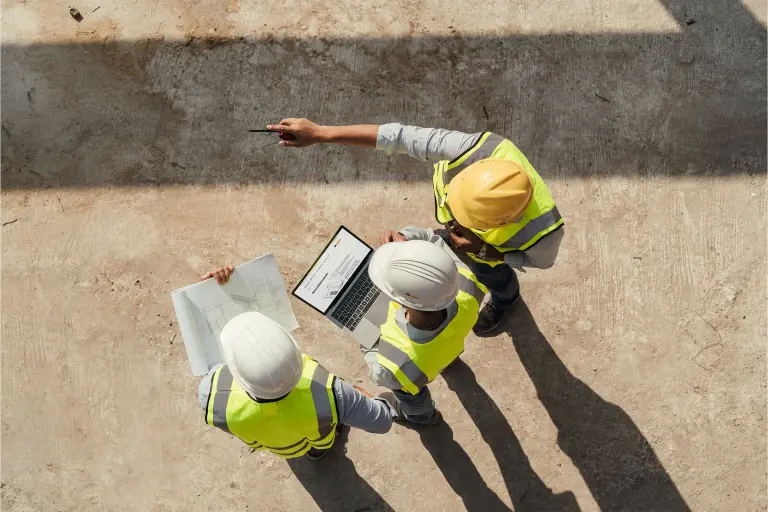 Drei Arbeiter auf einer Baustelle von oben