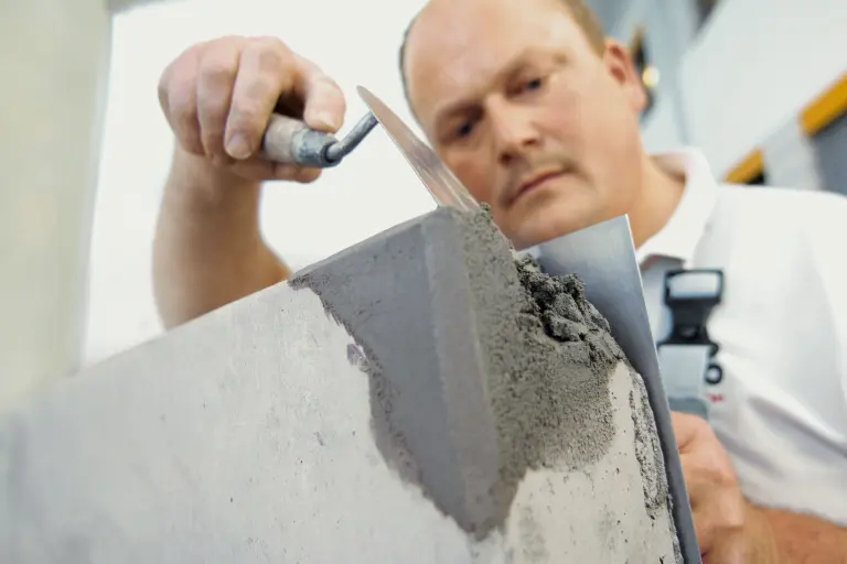 Fachhandwerker bessert eine Betonfassade mit Schnellraparaturmörtel aus
