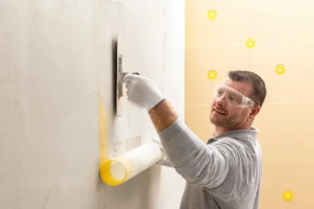 Foto Sto-Mitarbeiter der den zementfreien Unterputz StoLevell NeoAimS verarbeitet