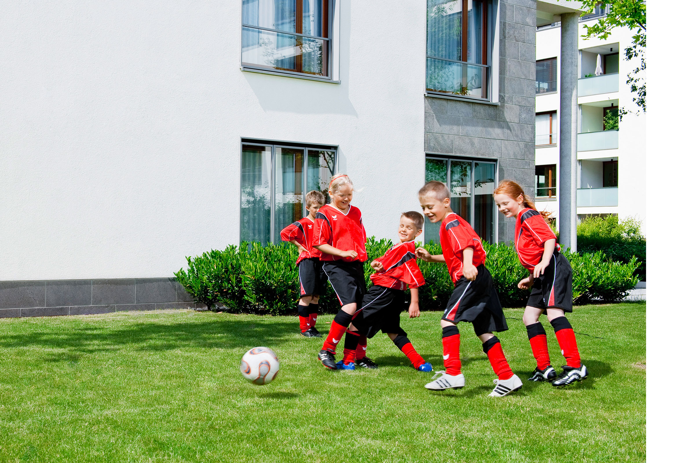 Kinder beim Fussball spielen vor Hausfassade