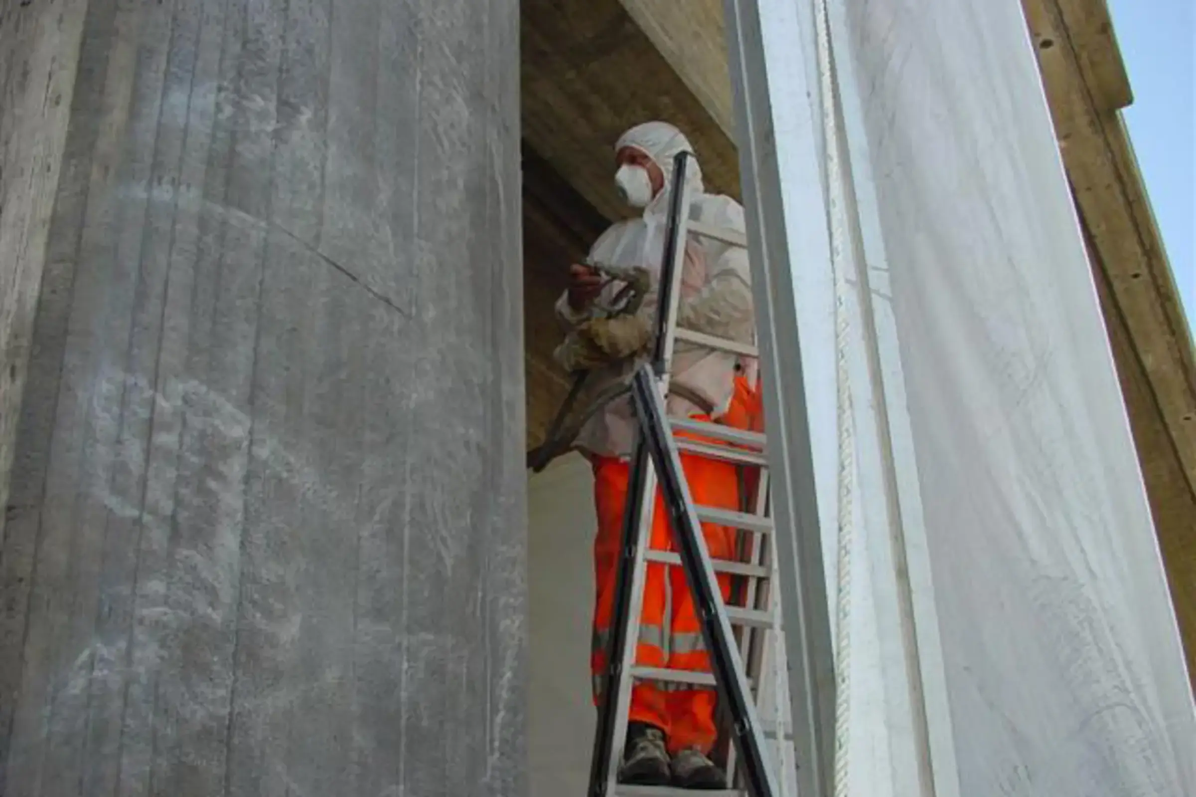 Un ouvrier spécialisé rénove le mur d'une galerie antibruit en béton