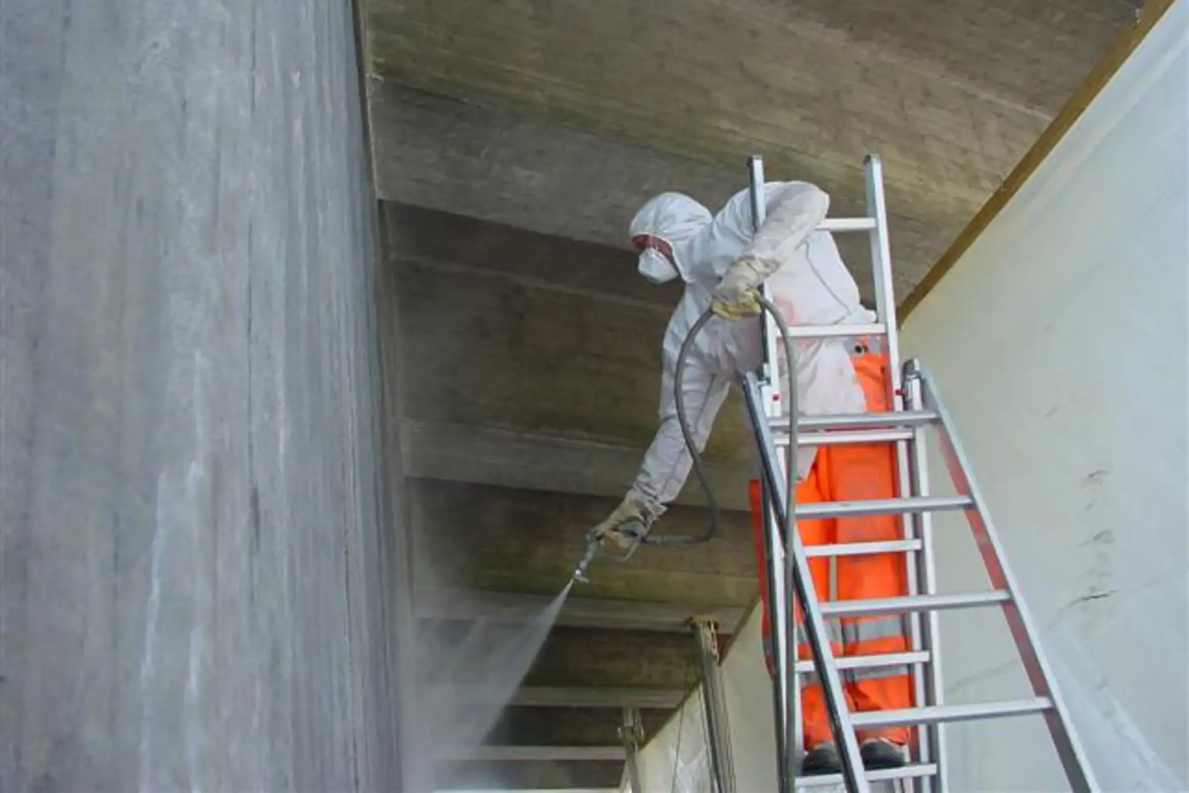 Un ouvrier qualifié pulvérise un hydrofuge sur un mur en béton