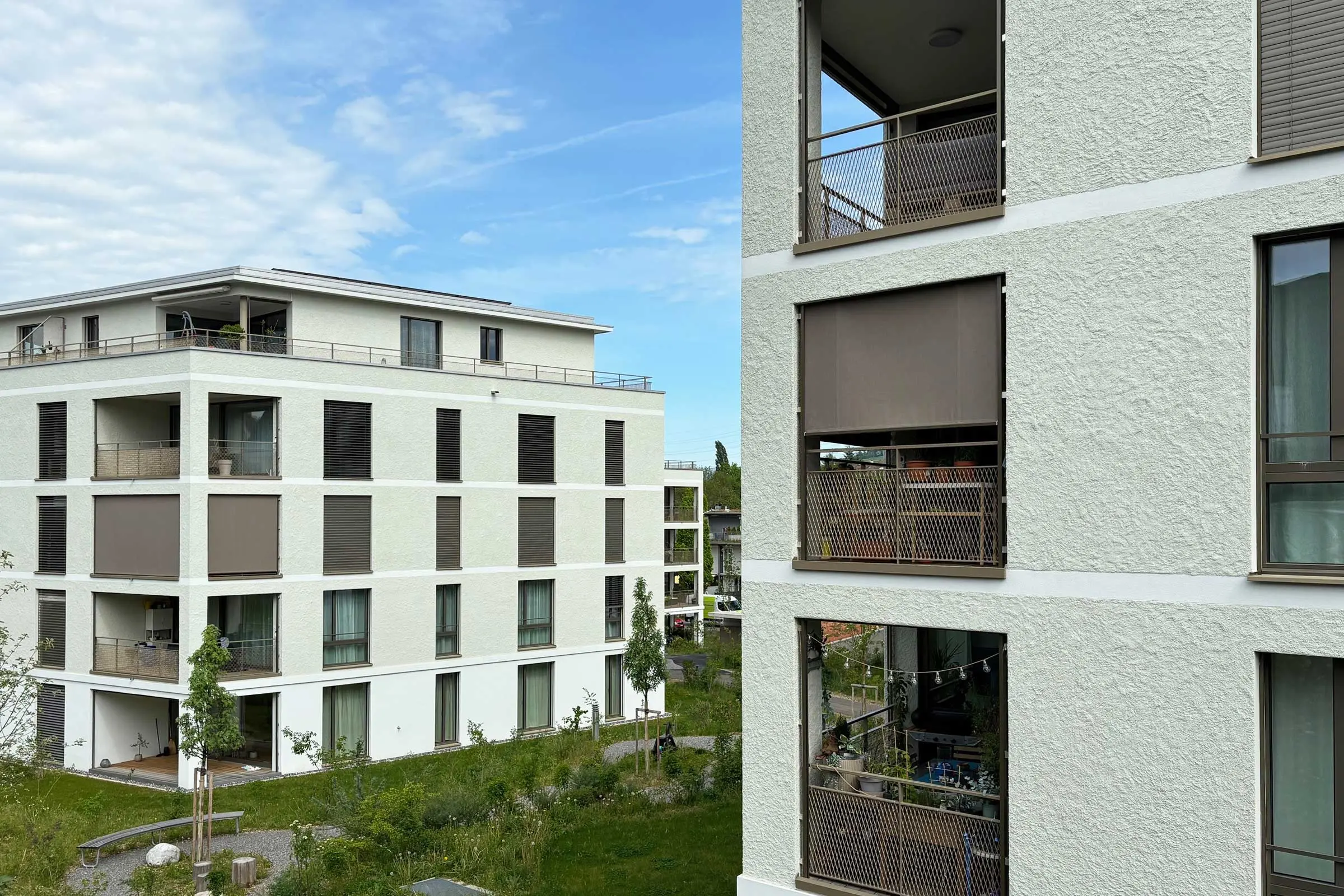 Mehrfamilienhäuser mit hellgrüner Fassade und braunen Fenstern