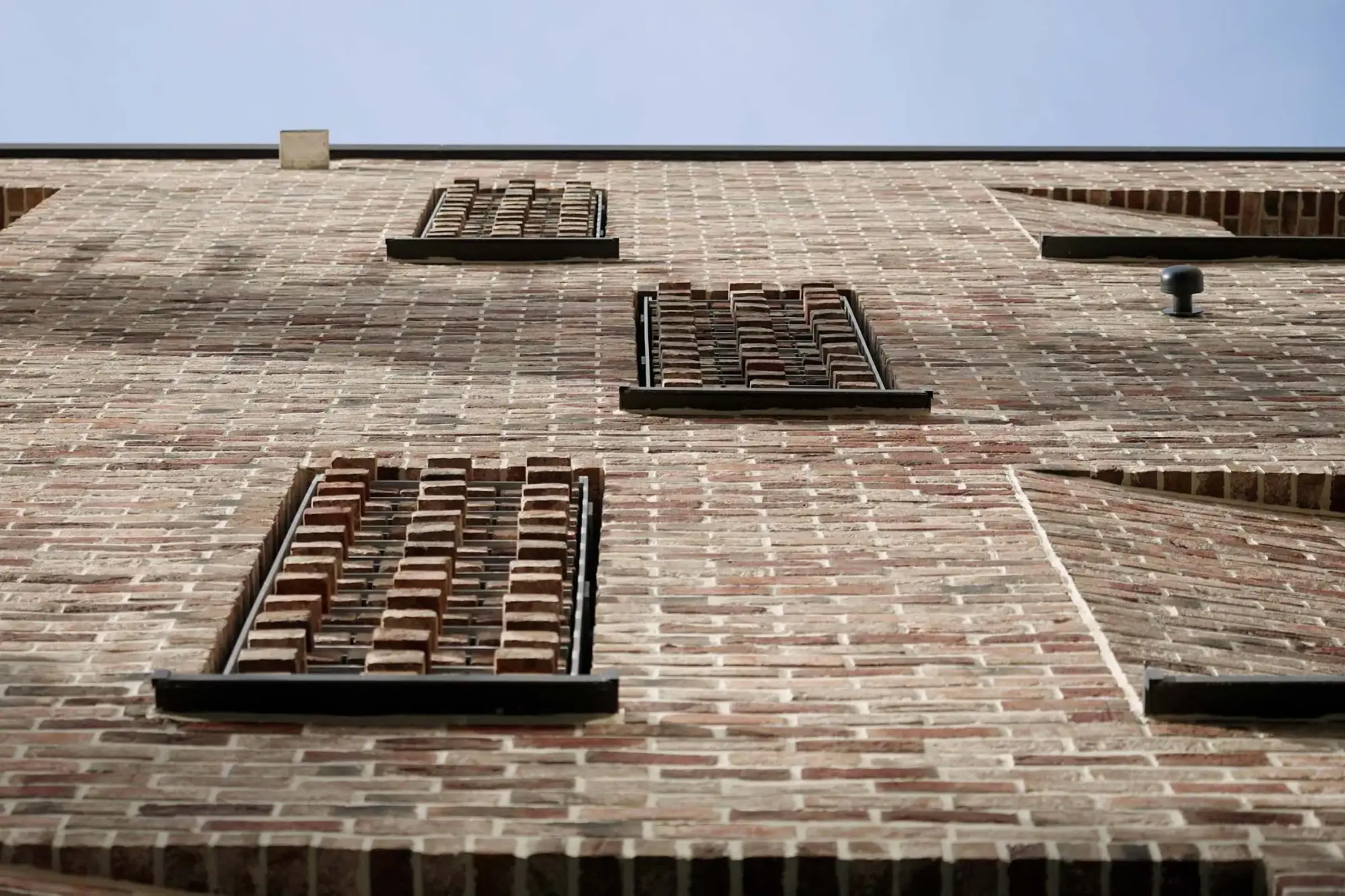 Nahaufnahme einer Fassade mit rötlichem Klinker von unten