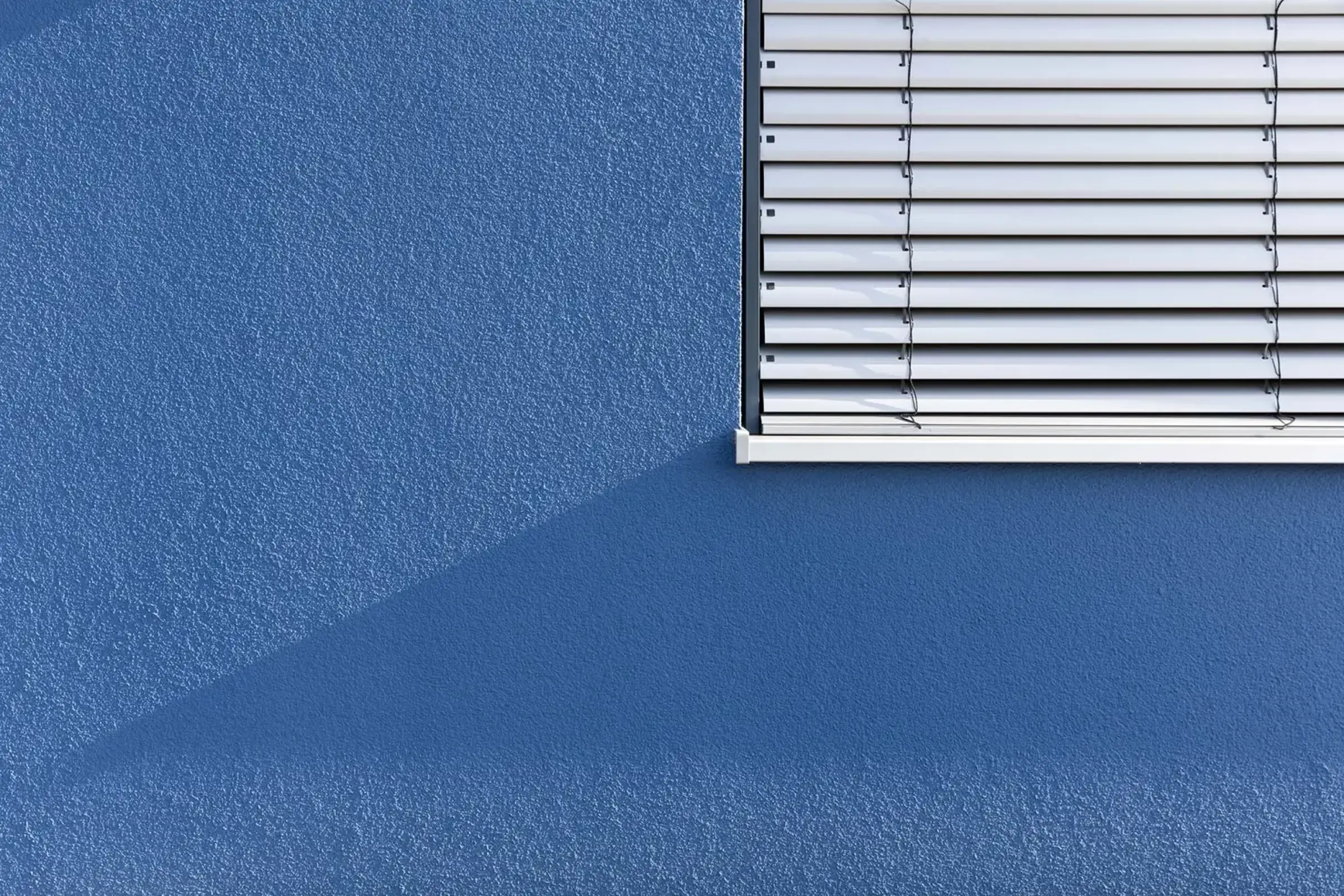 Ausschnitt Fenster mit Fassade in blau mit der Fassadenfarbe StoColor Dryonic S gestrichen