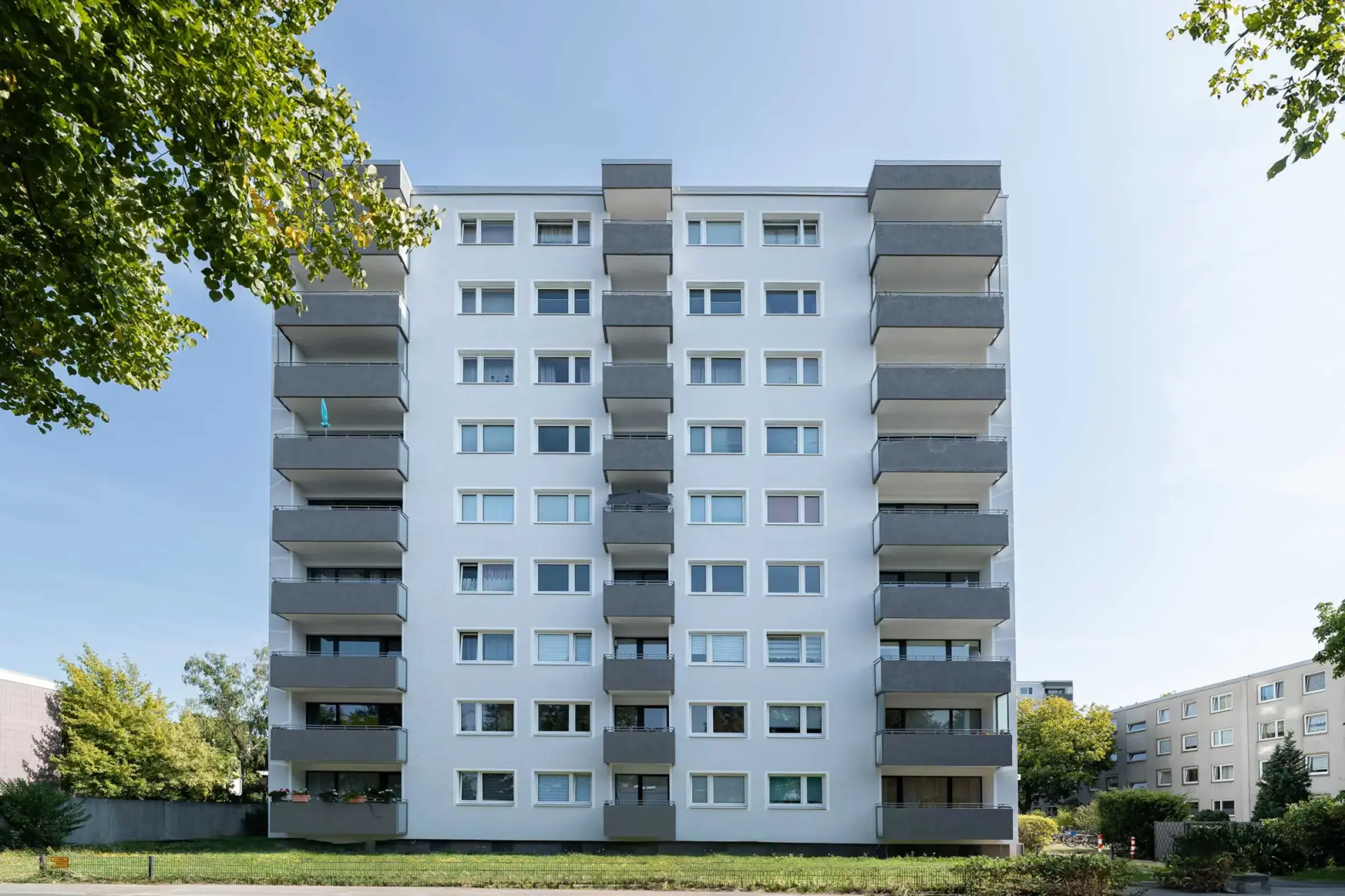 Frontansicht saniertes Hochhaus mit grauen Balkonen