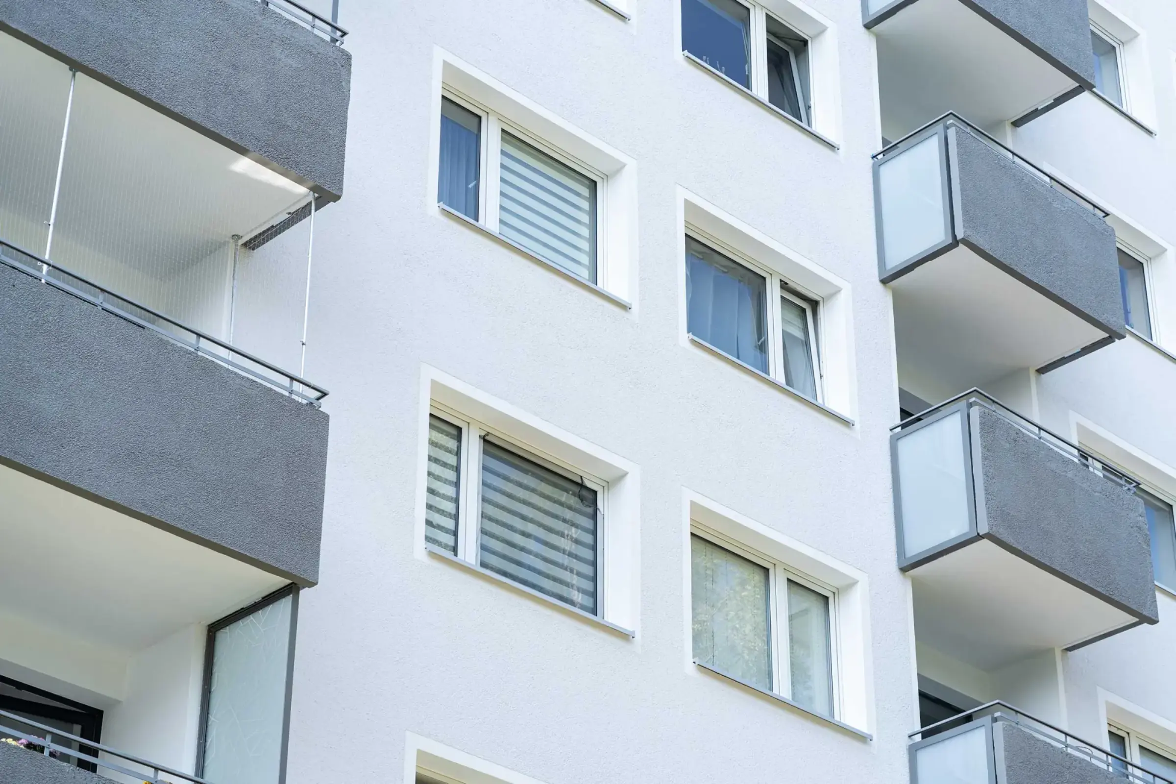 Nahaufnahme Fassade eines Hochhauses mit weissem Putz und grauen Balkonen