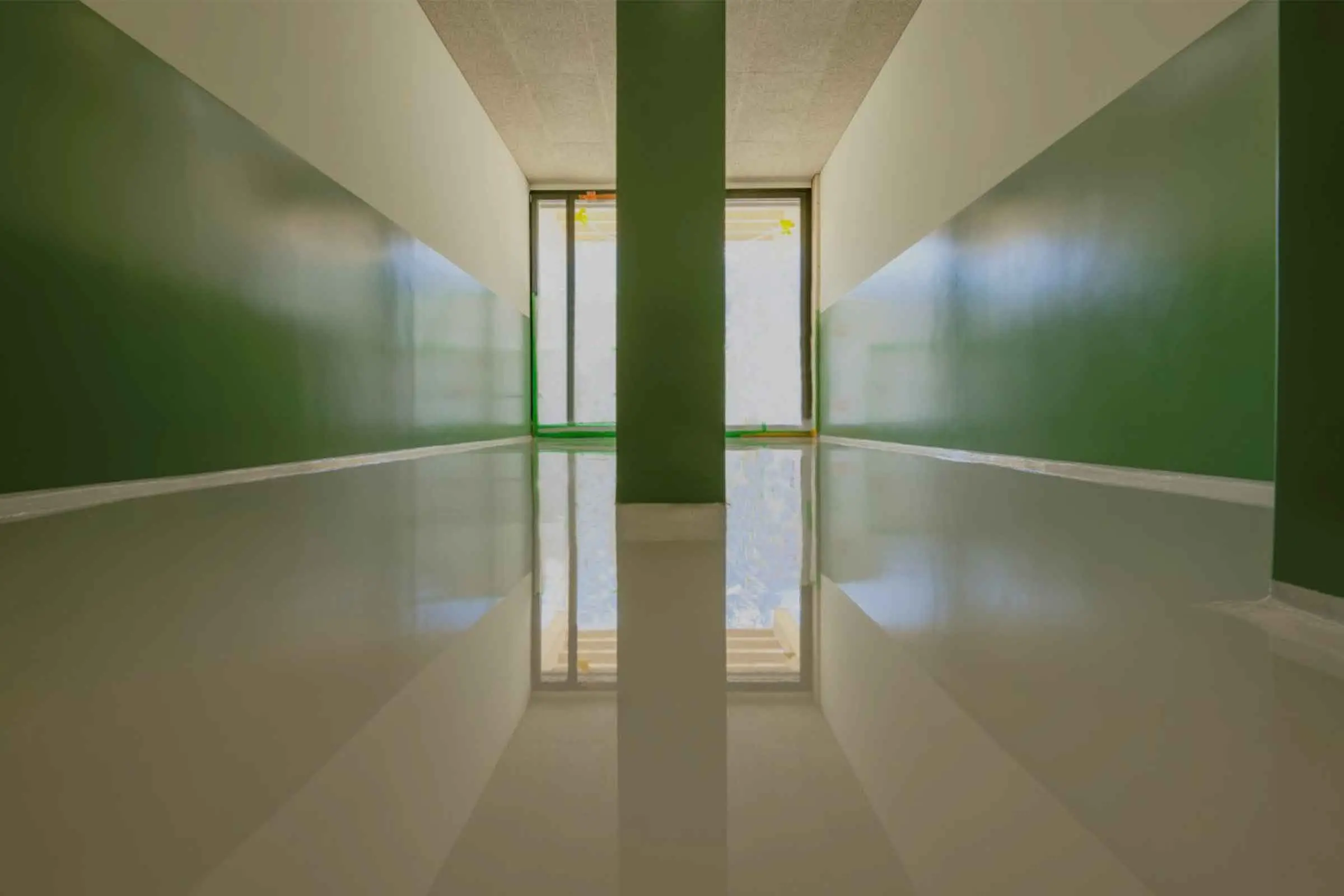 Hall d'école avec un revêtement de sol clair et un revêtement mural vert sans joints