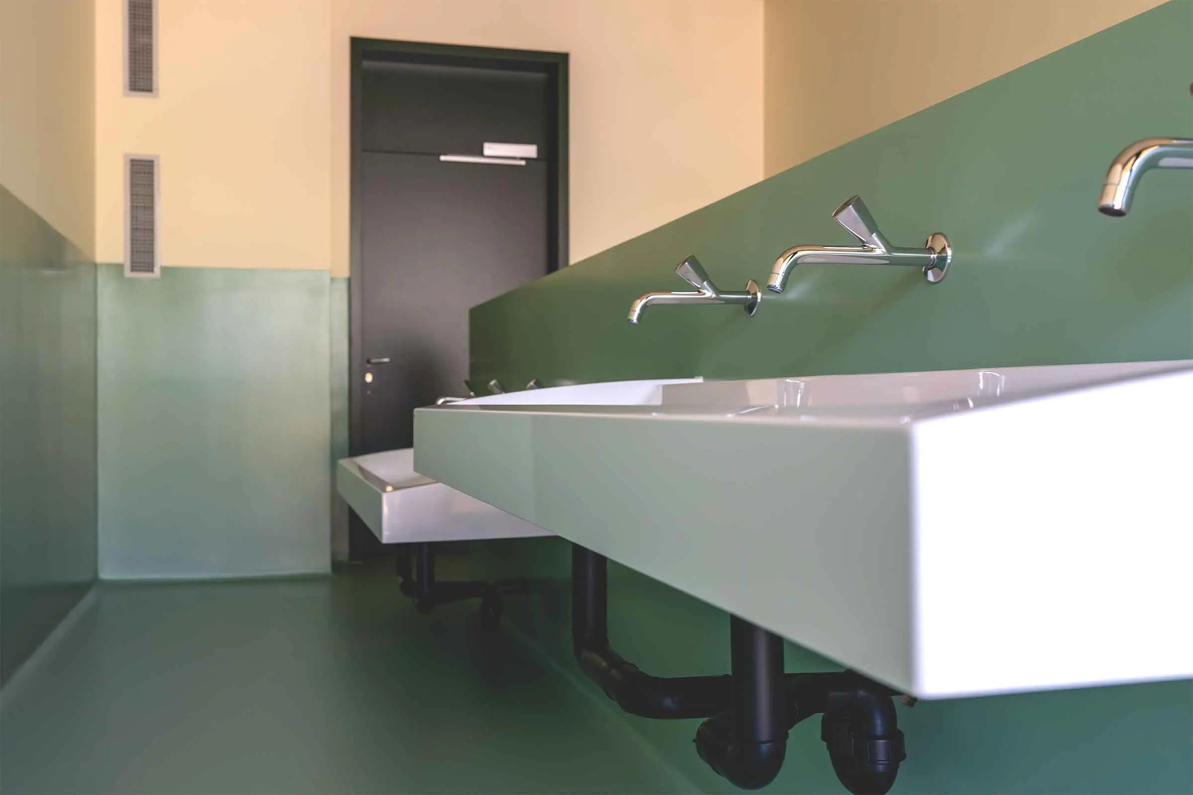 Salle d'eau avec lavabos blancs et revêtement mural vert sans joints