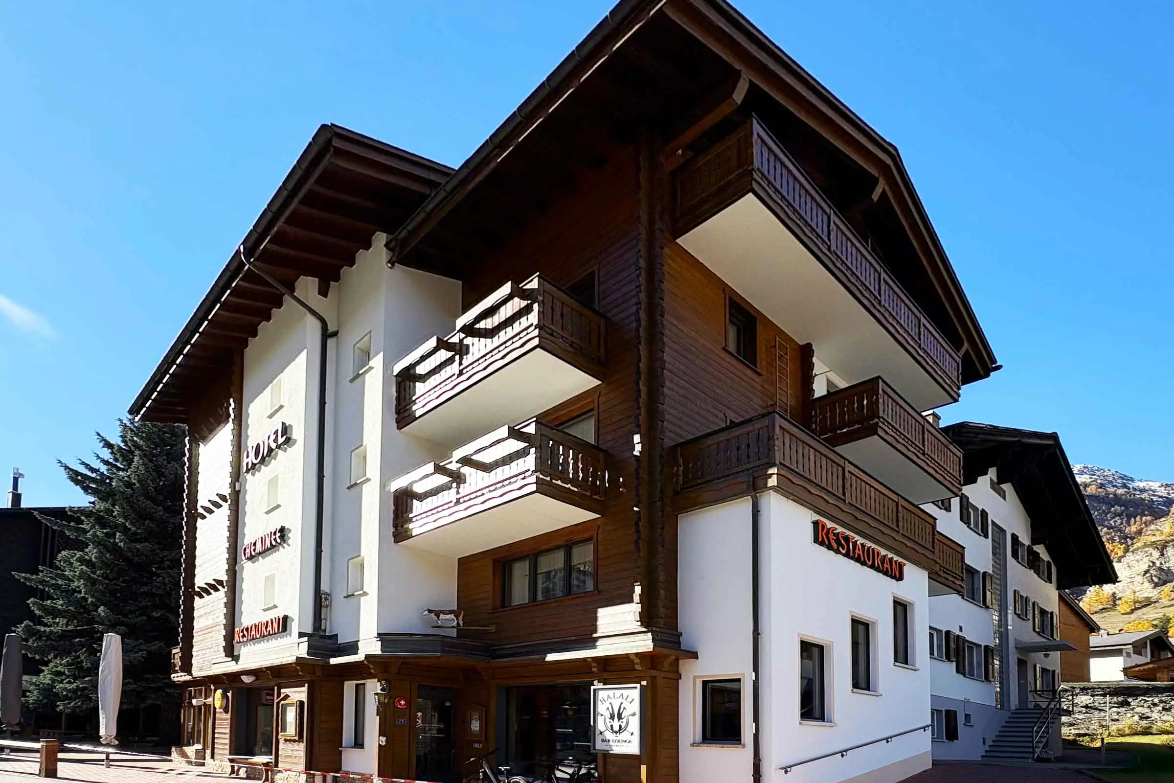 Eckansicht von unten Hotel in Zermatt mit Fassade aus Holzverkleidung und heller Fassadenbeschichtun