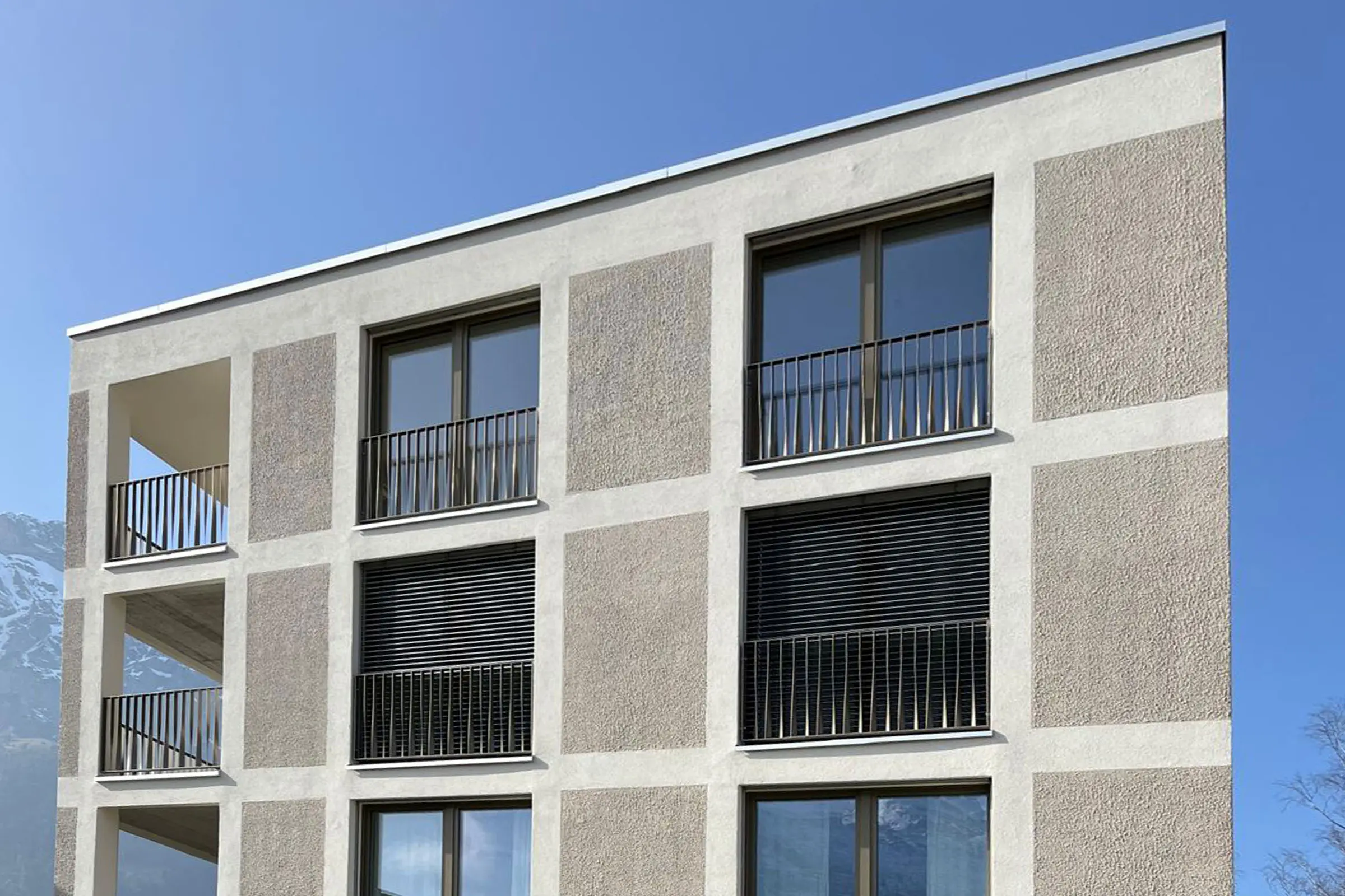 Fassade Mehrfamilienhaus mit Fensterfront mit beigem Putz und braunem Putz