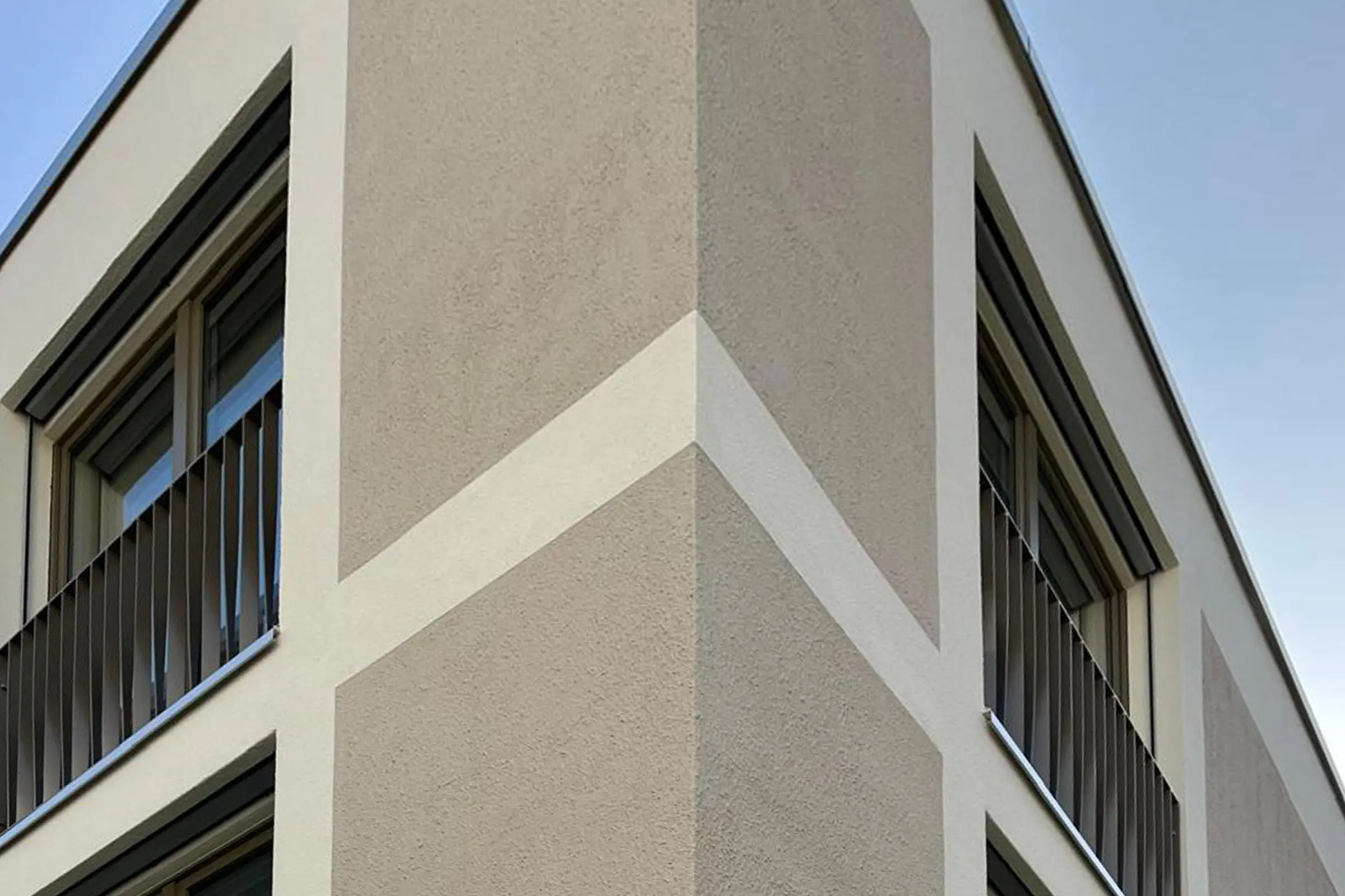 Eckansicht von Mehrfamilienhaus mit beigem und braunem Putz