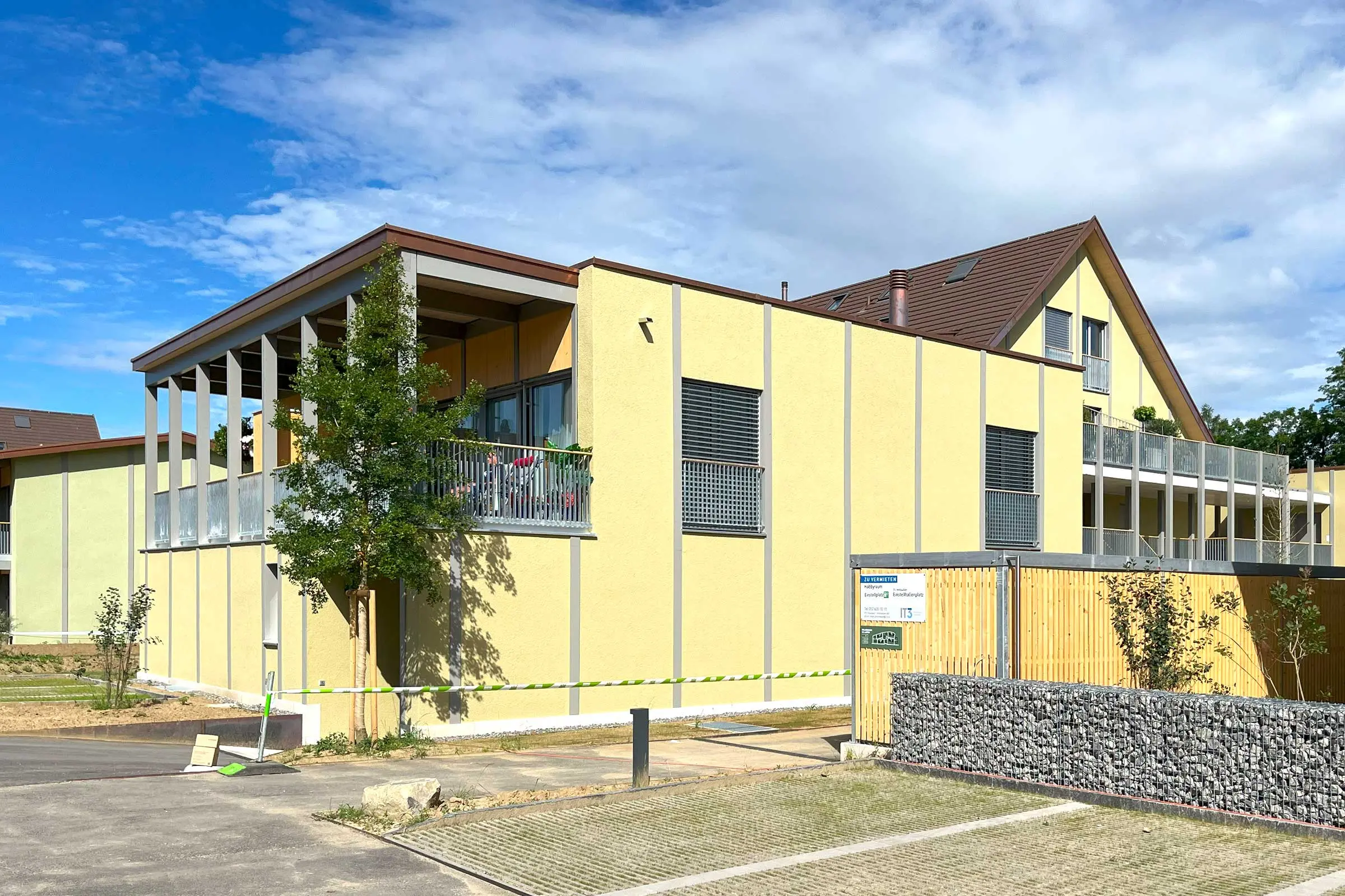 Hinteransicht Mehrfamilienhaus mit gelber Fassade und Balkon