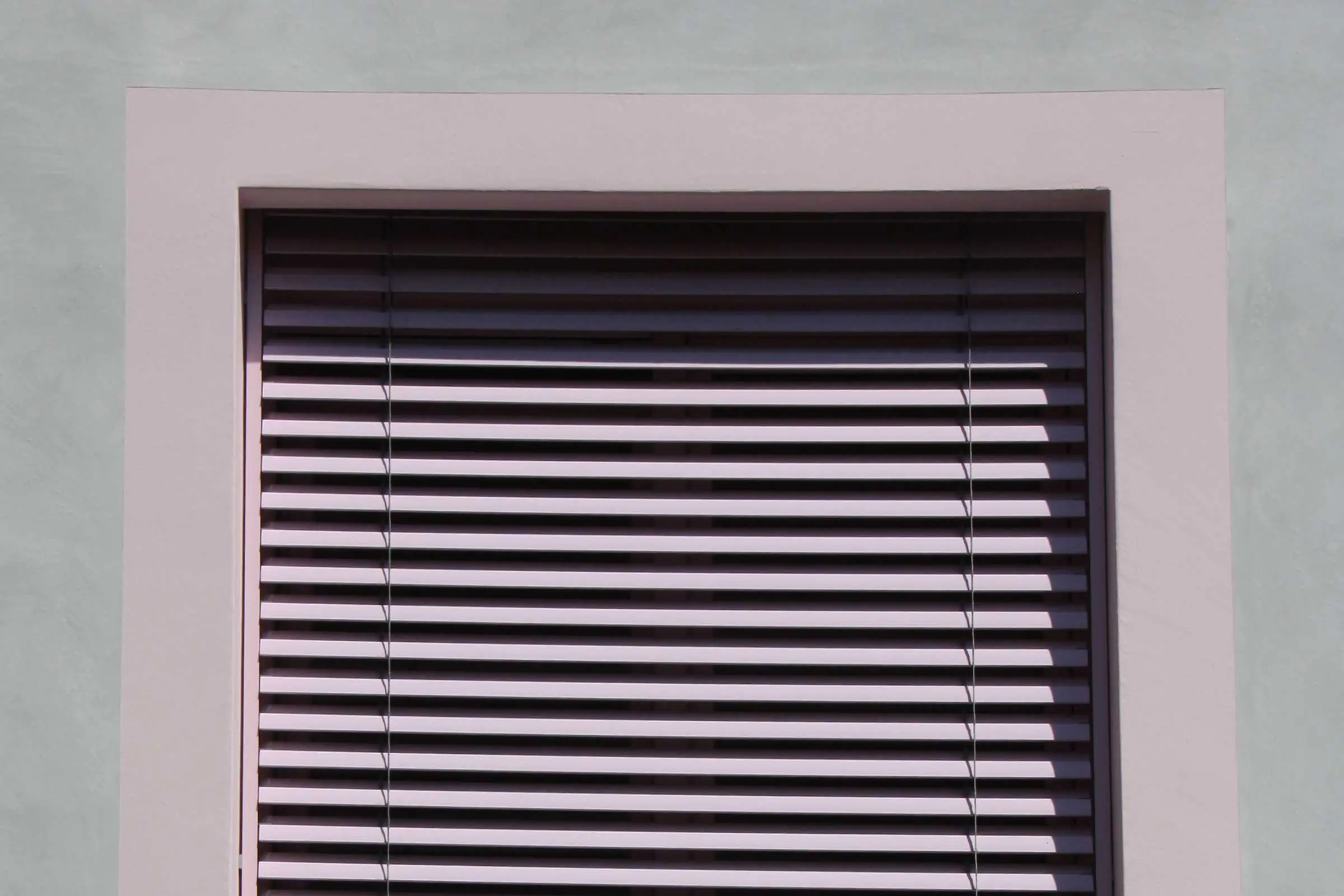 Detaiaufnahme Fenster mit rosa Umrandung und rosa Jalousien