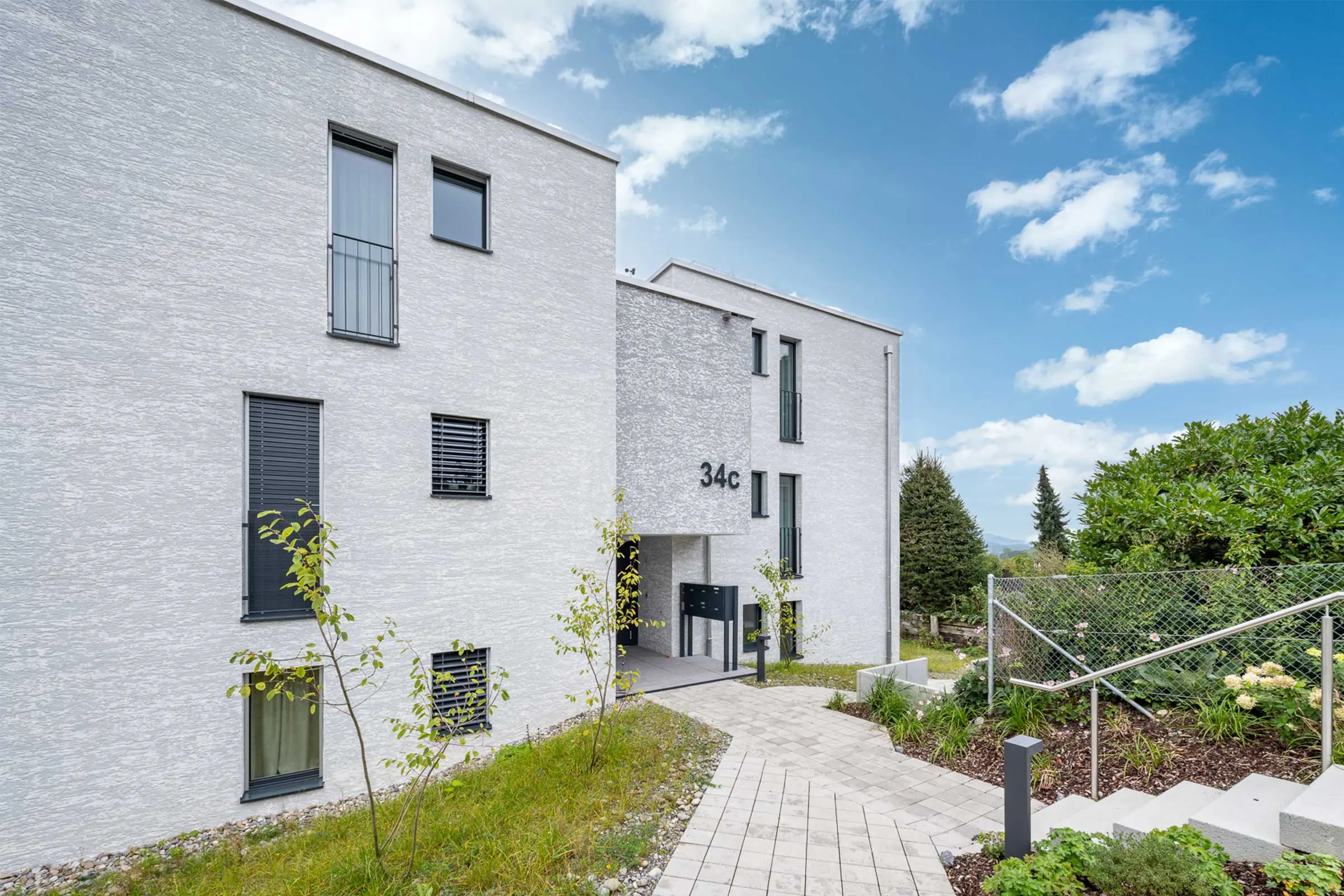 Seitenansicht MFH in Kloten mit Fassadenbeschichtung StoMiral Edelkratzputz beige 