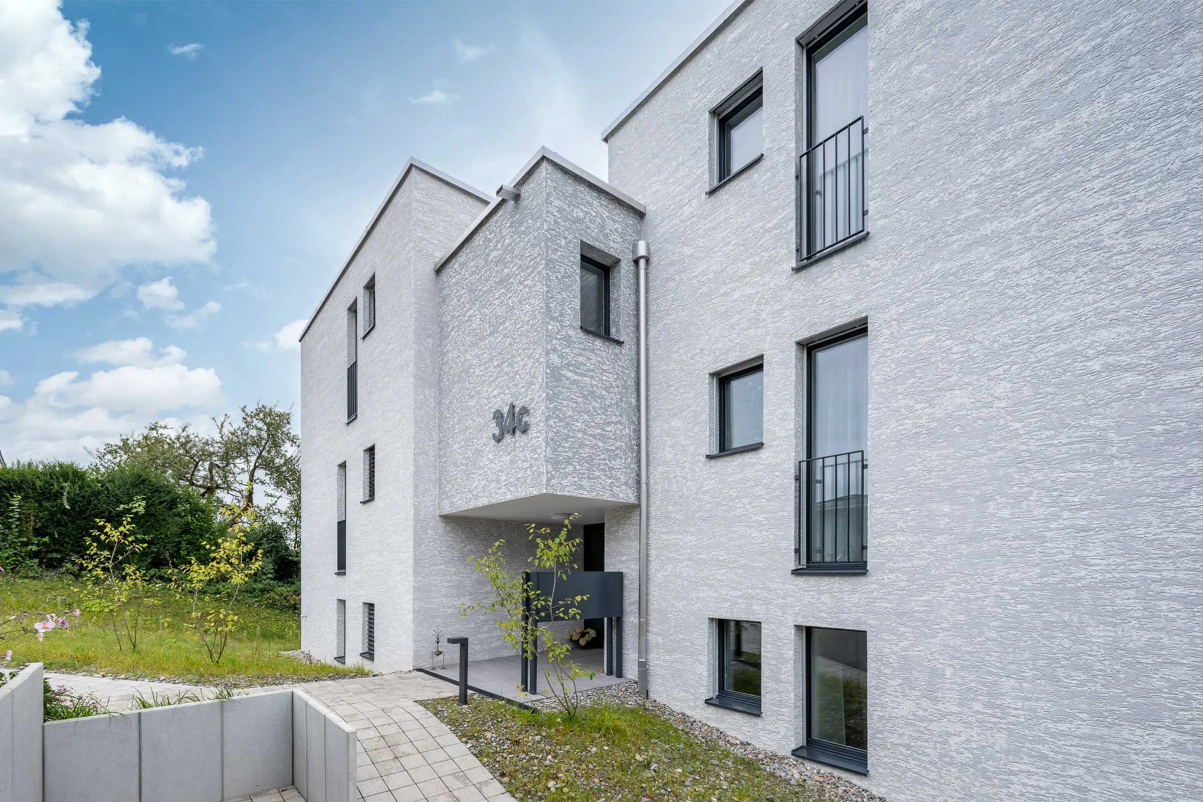 Seitenansicht MFH in Kloten mit Fassadenbeschichtung StoMiral Edelkratzputz beige