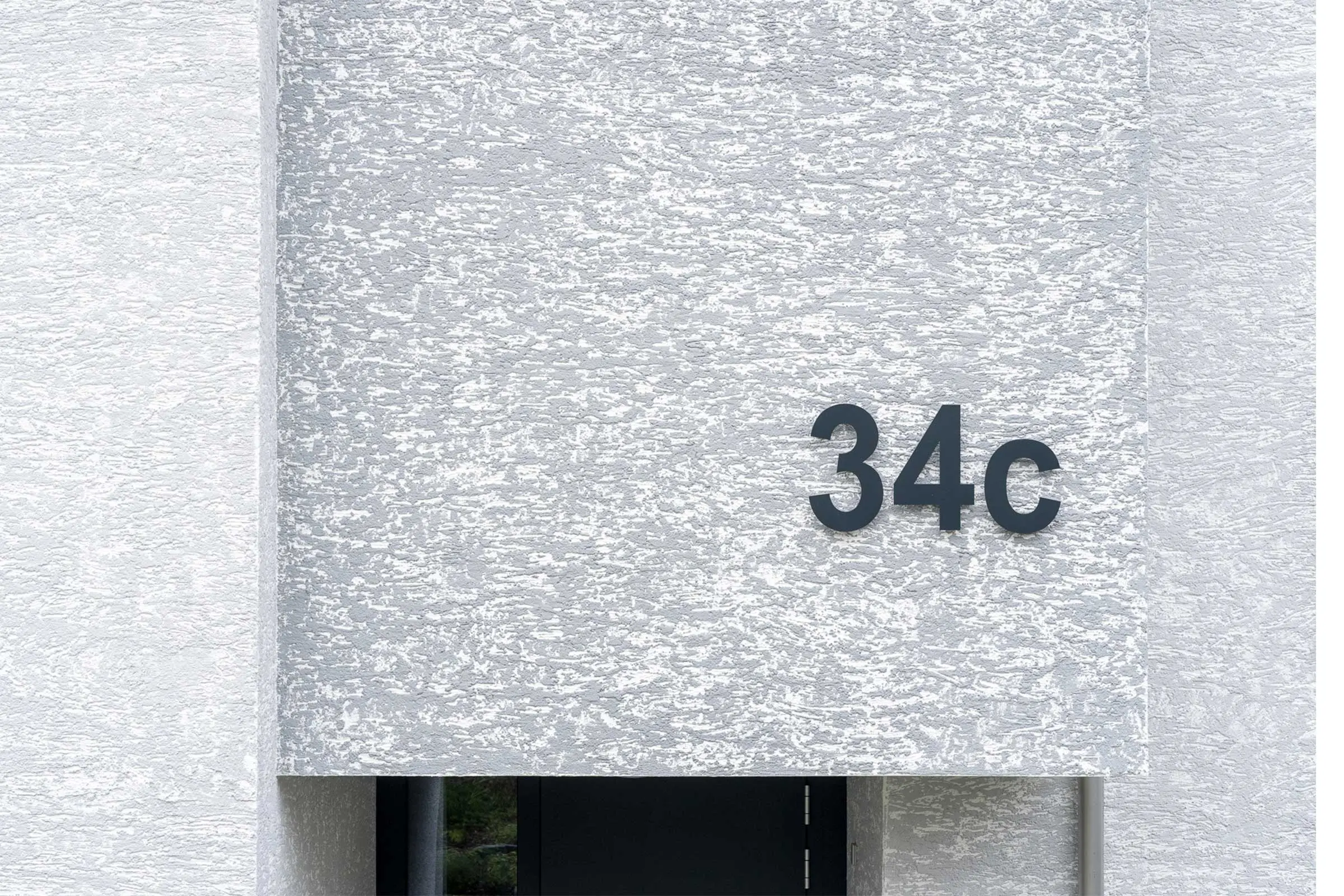 Ausschnitt einer Fassaden mit Edelkratzputz StoMiral in beige mit Hausnummer