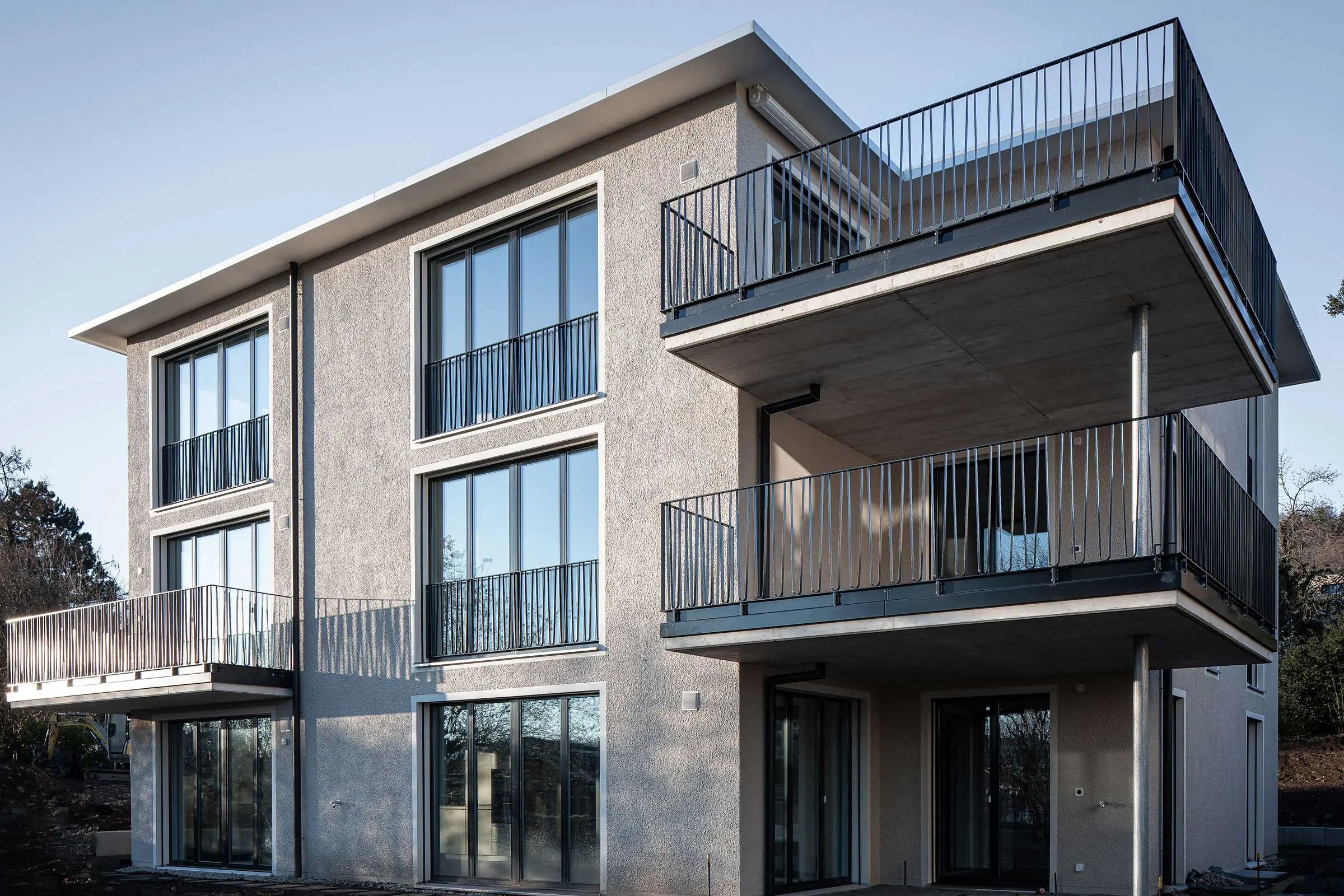 Echansicht Mehrfamilienhaus mit Fensterfronten und Balkonen in heller Putzfassade