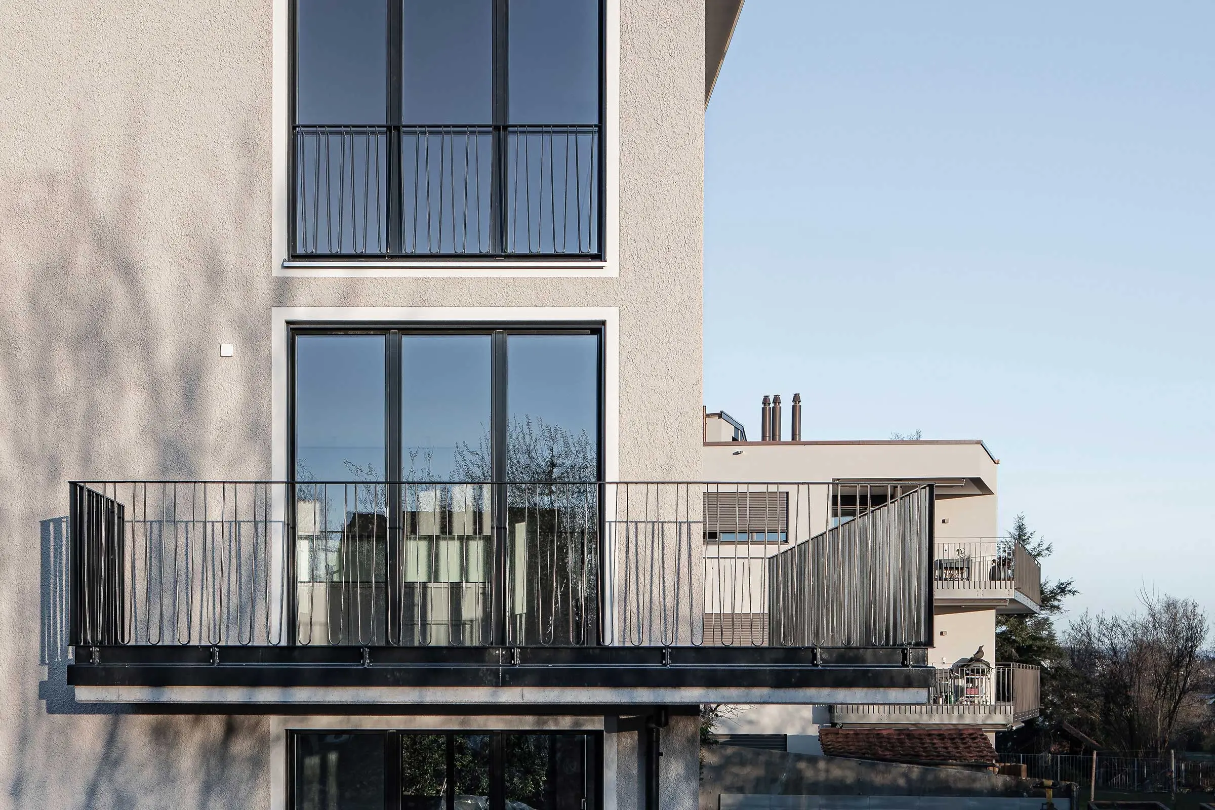 Seitenansicht Fassade mit Fensterfront  und Balkon mit hellem Putz 