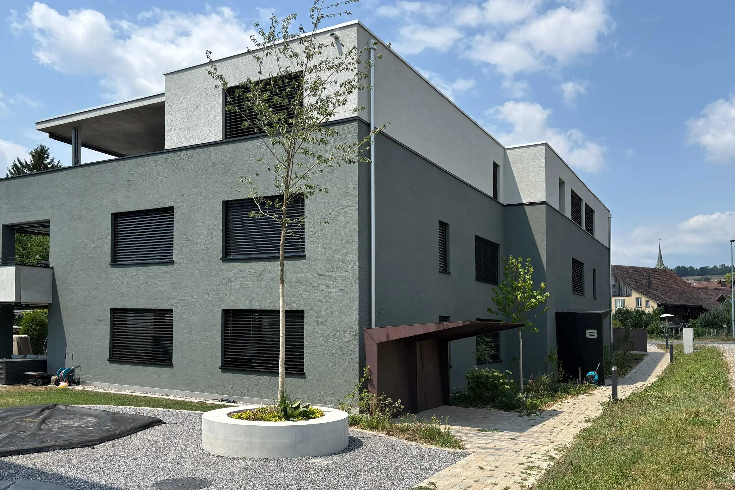 Mehrfamilienhaus mit grüner Fassade unten und heller Fassade im oberen Stockwerk
