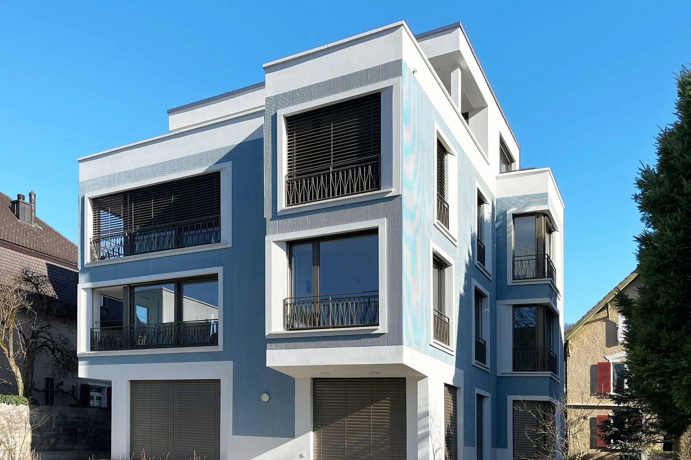 MFH mit blauer Fassade in der Putztechnik StoSignaure und weissen Fensterumrandungen mit StoDeco