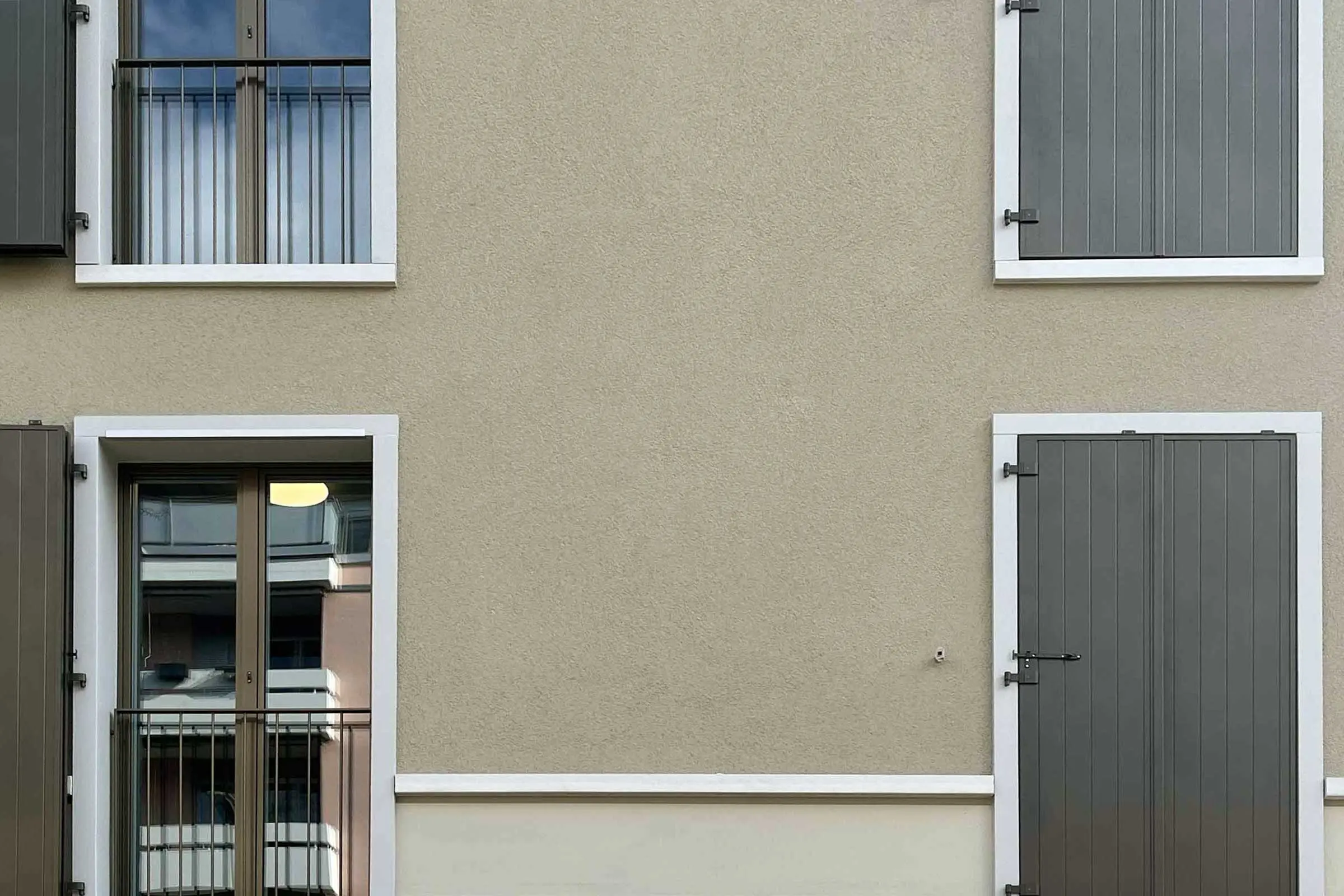 Braune Hausfassade mit vier Fenstern mit heller Fensterumrandung