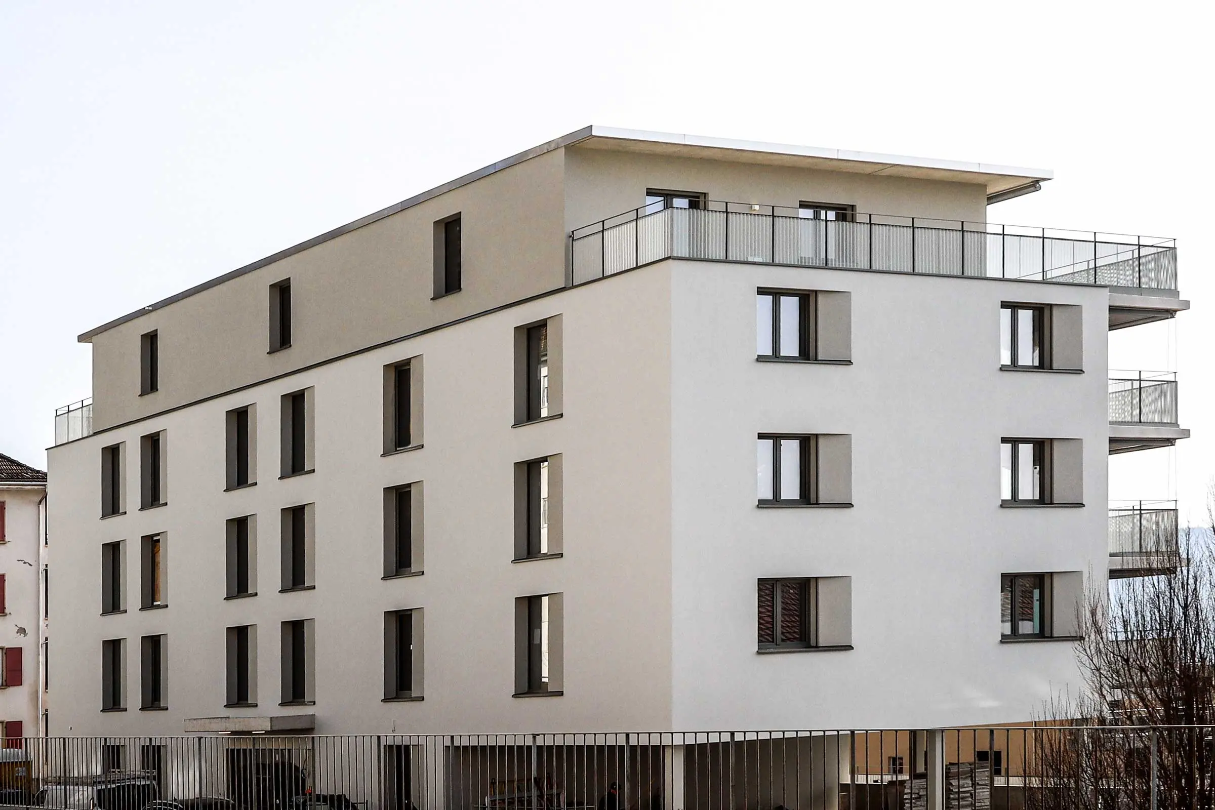 Hintere Ansicht von mehrstöckigem Mehrfamilienhaus mit heller Fassadenbeschichtung