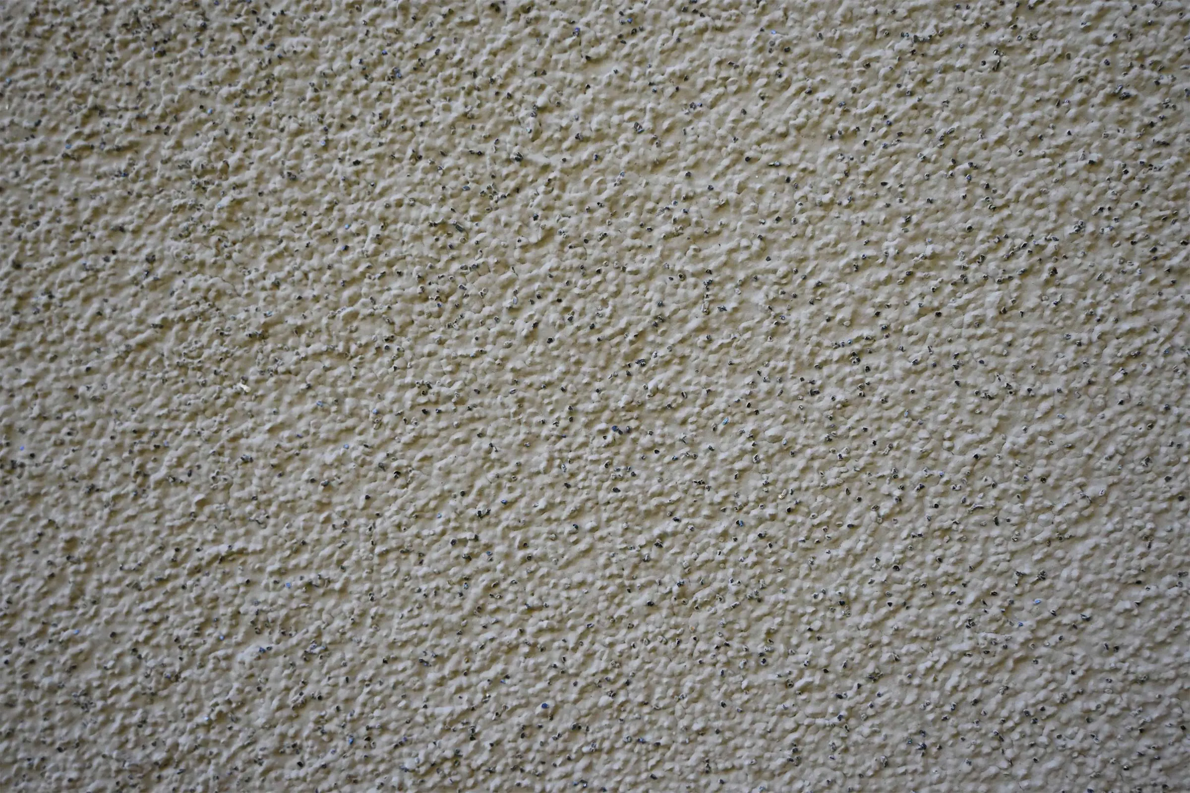 Nahaufnahme helle Putzfassade mit Technik Signature mit dunklem Granulat aus Siliciumcarbid