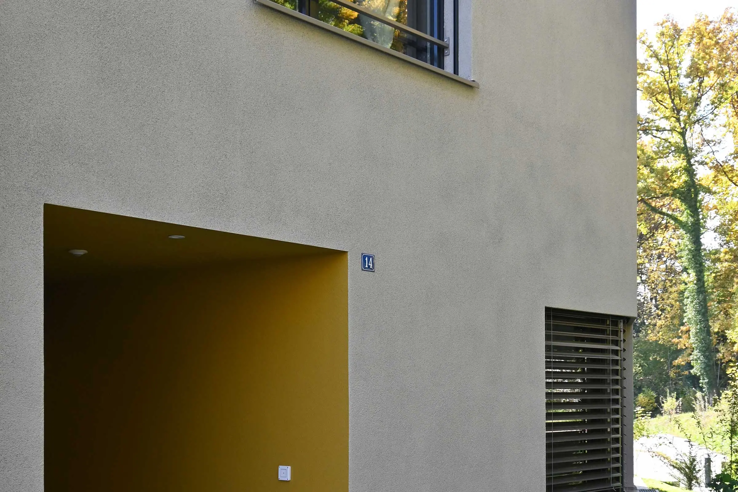 Eingangsbereich mit Putz innen in Orange und heller Putzfassade