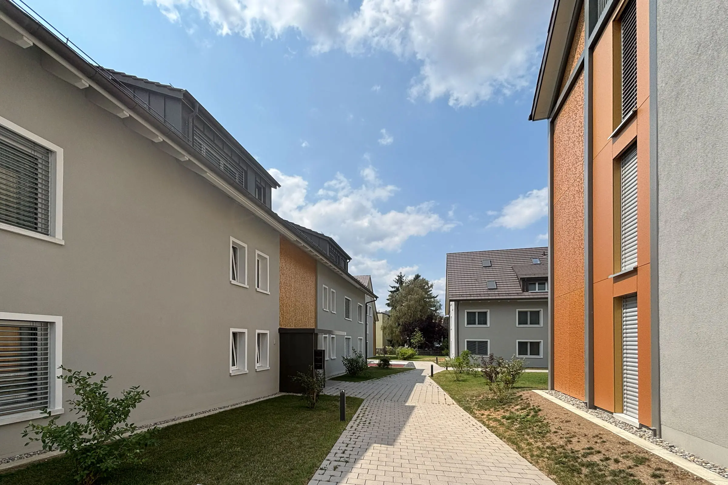 Wohnüberbauung mit vier Mehrfamilienhäusern mit hellgrauer Fassade und hellen Fensterumrandungen