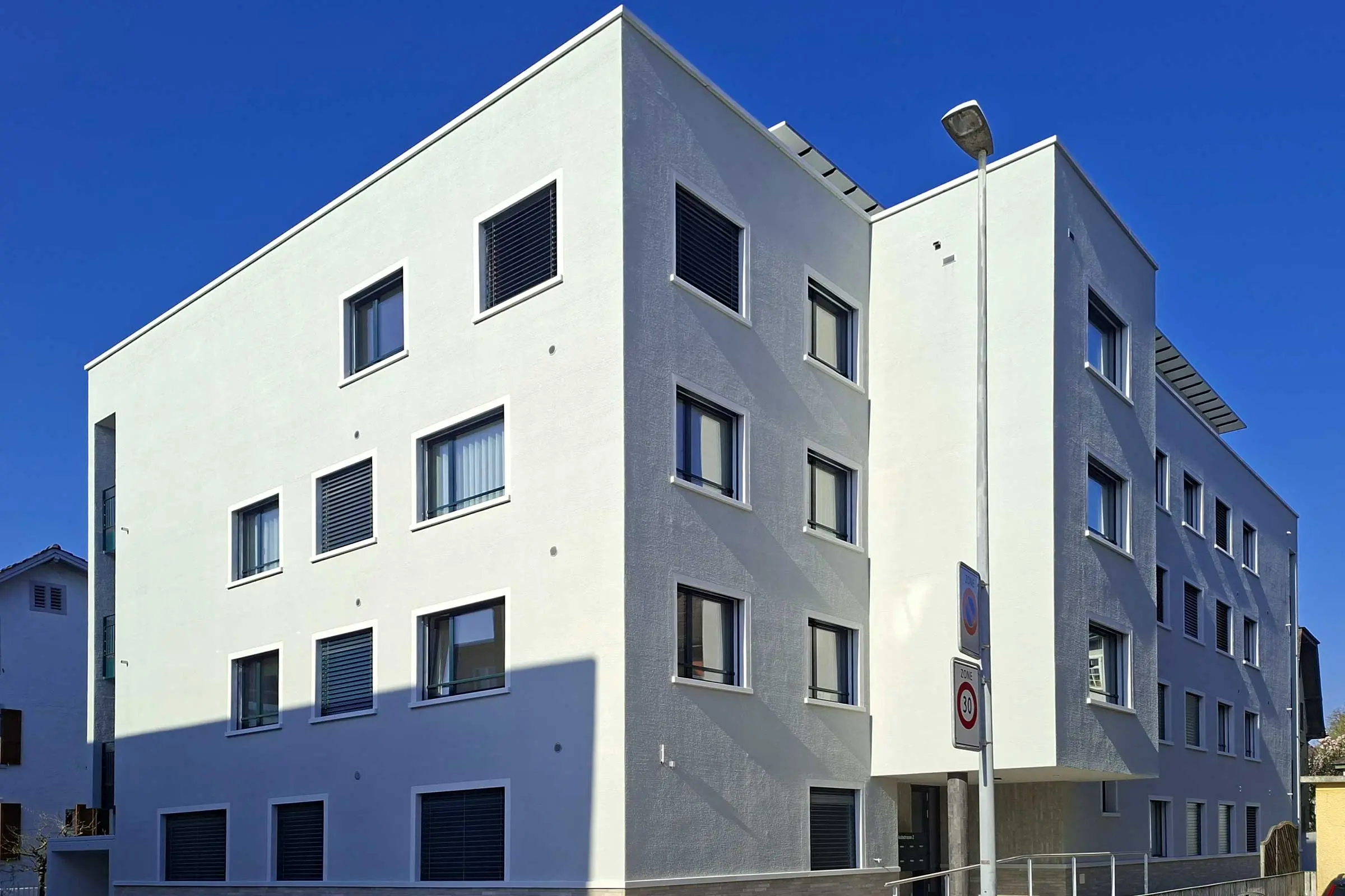 Eckansicht von MFH mit hellem Putz und hellen Fensterumrandungen aus StoDecoelementen