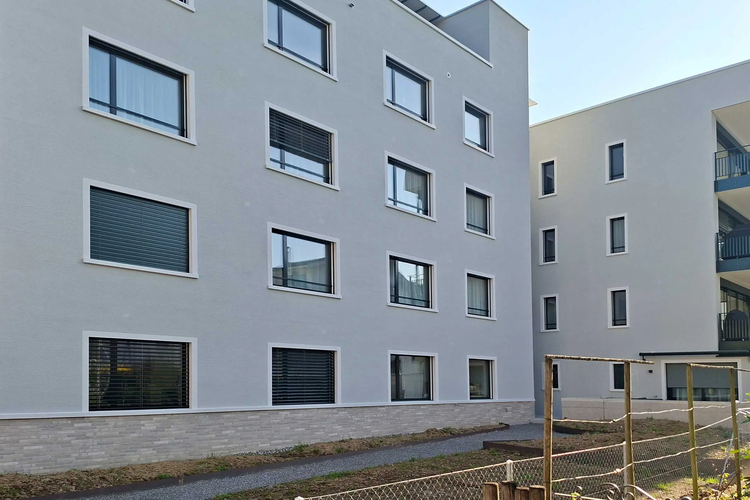 Frontansicht von MFH mit hellem Putz und hellen Fensterumrandungen aus StoDecoelementen