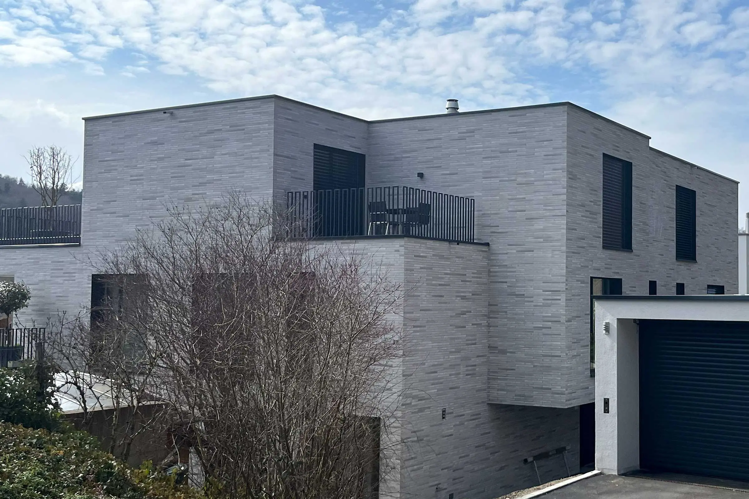 Ansicht hinten von Mehrfamilienhaus mit Klinkerfassade in grau-beige