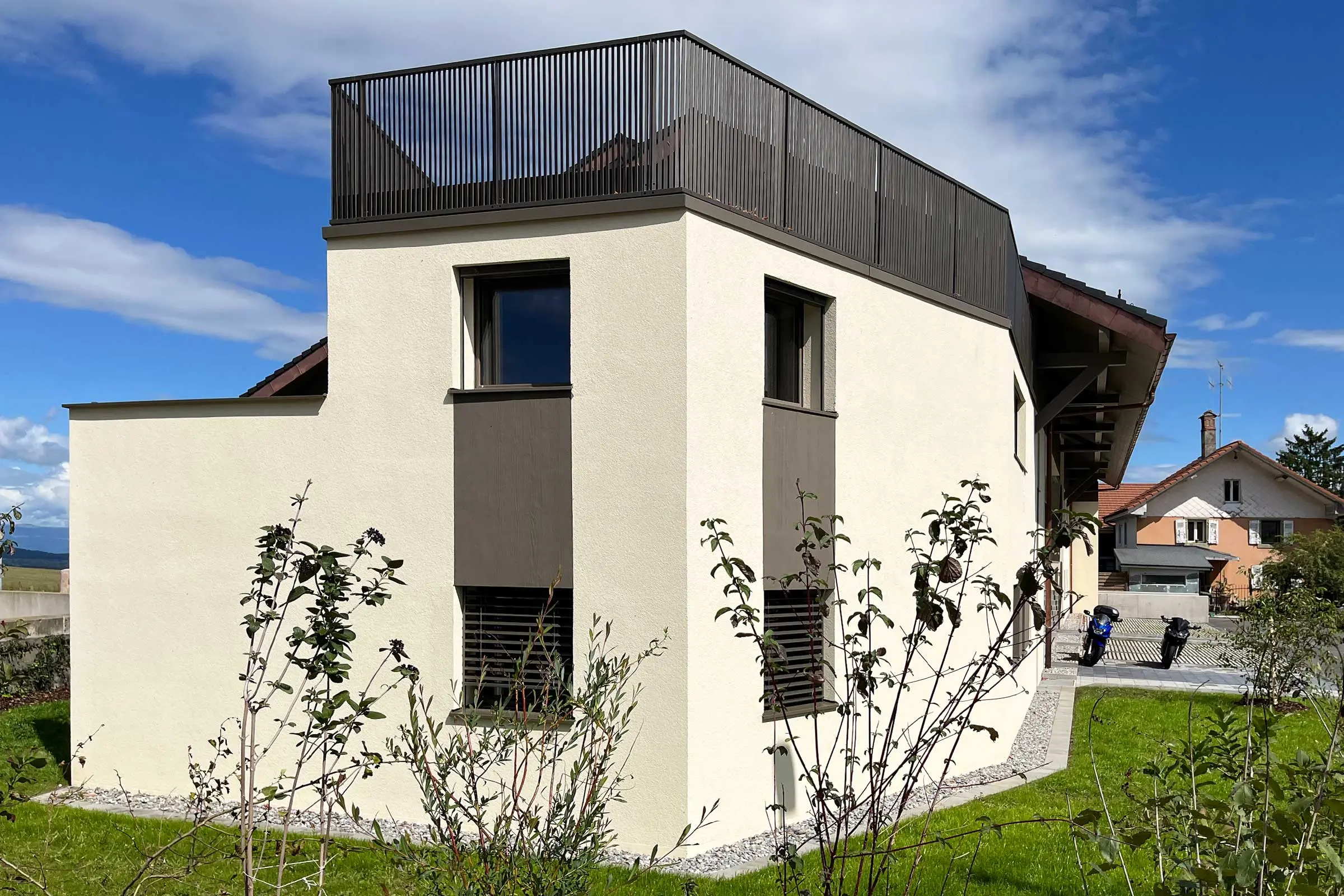 Dos d'un immeuble d'habitation avec fenêtres et balustrade de balcon en haut avec enduit clair