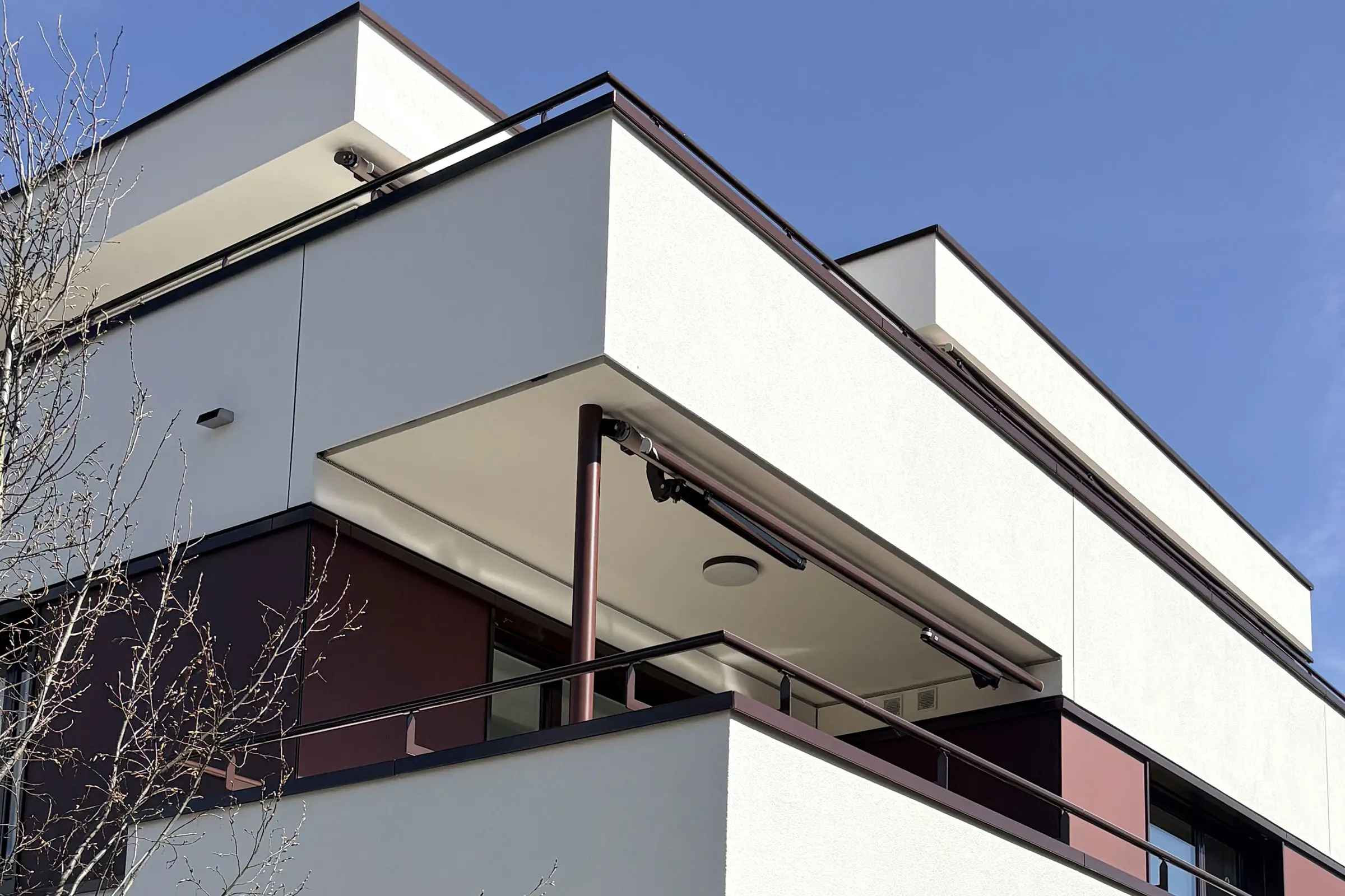 Ansicht eines Balkons von einem Mehrfamilienhaus mit einer Fassade aus roten Fassadenplatten und hel
