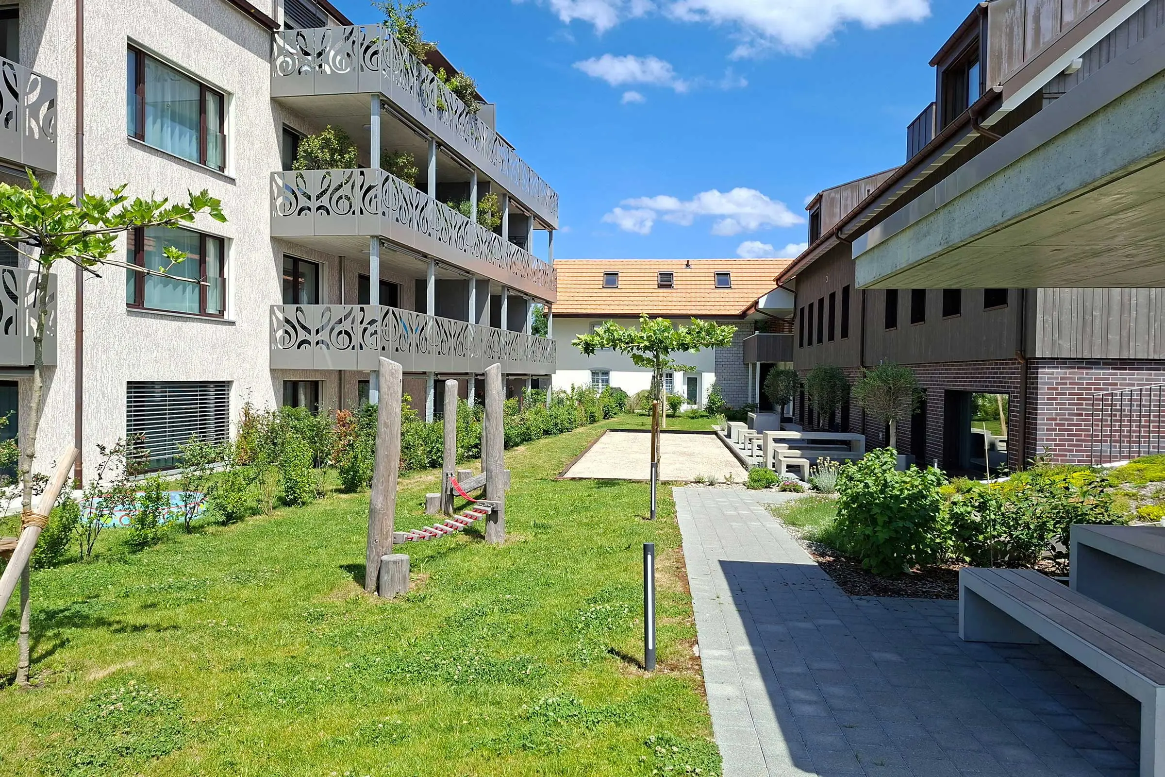 Mehrfamilienhaus mit beiger Putzfassade und grauen Balkonverkleidungen aus Metall