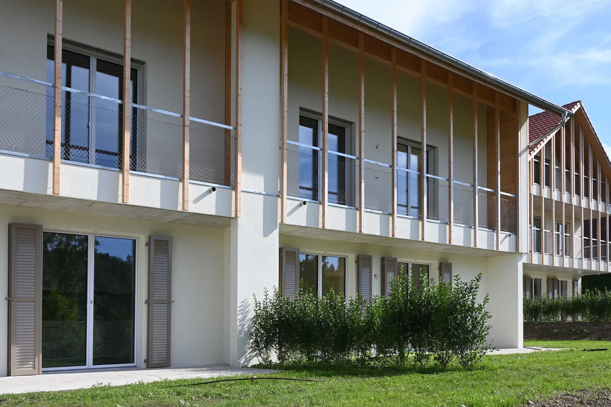 Ansicht Balkone von MFH mit einer Fassade mit Holzlatten auf weisser Putzfassade