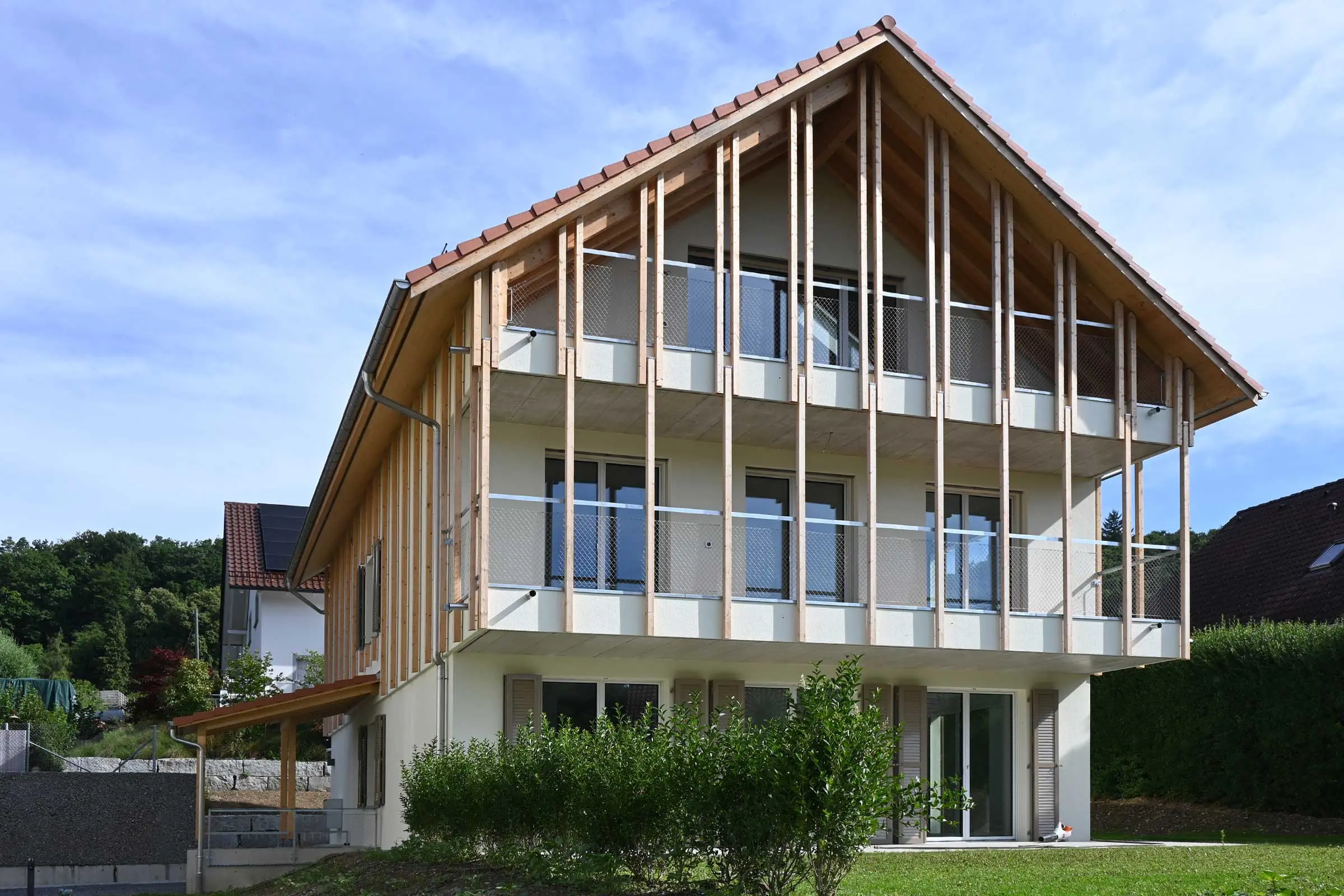 Haus aus einem Gebäudecomplex mit Neubauten mit Holzlatten auf heller Putzfassade