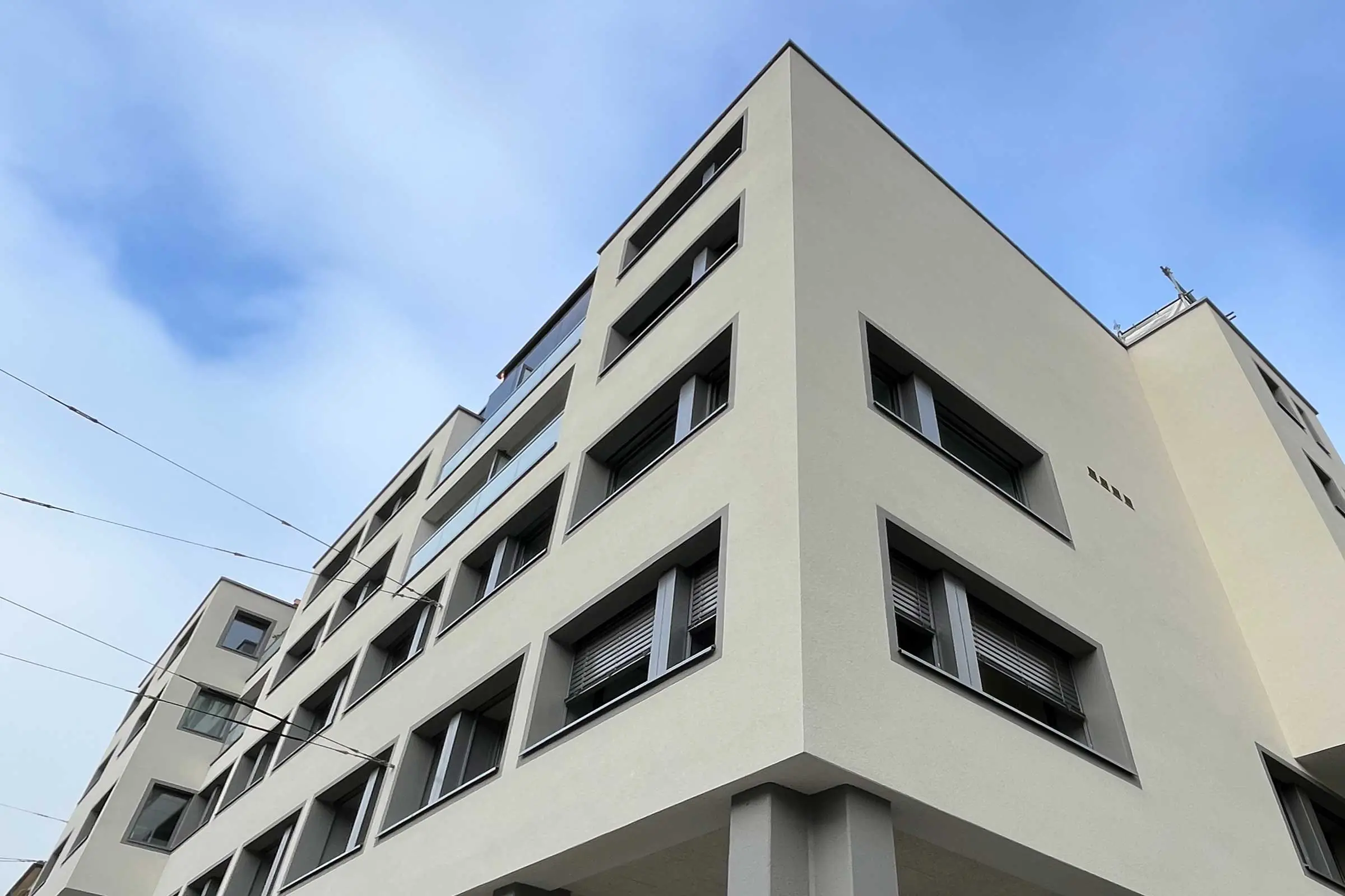 Immeuble collectif avec façade en crépi clair et encadrements de fenêtres de couleur grise contrasté