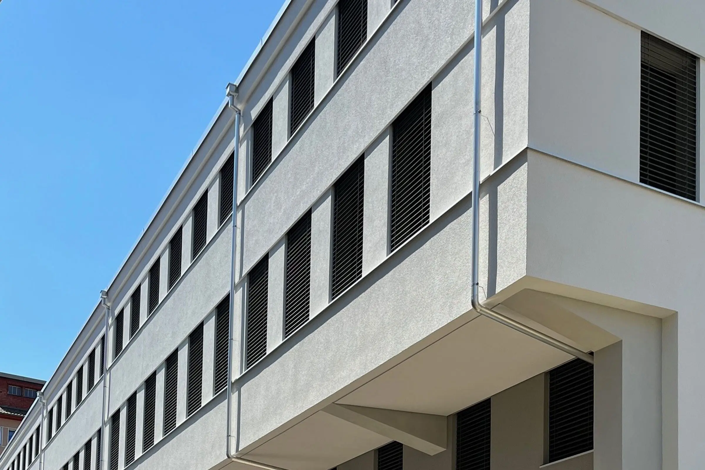 Seitenansicht Verwaltungsgebäude SIG Neuhausen mit heller Putzfassade