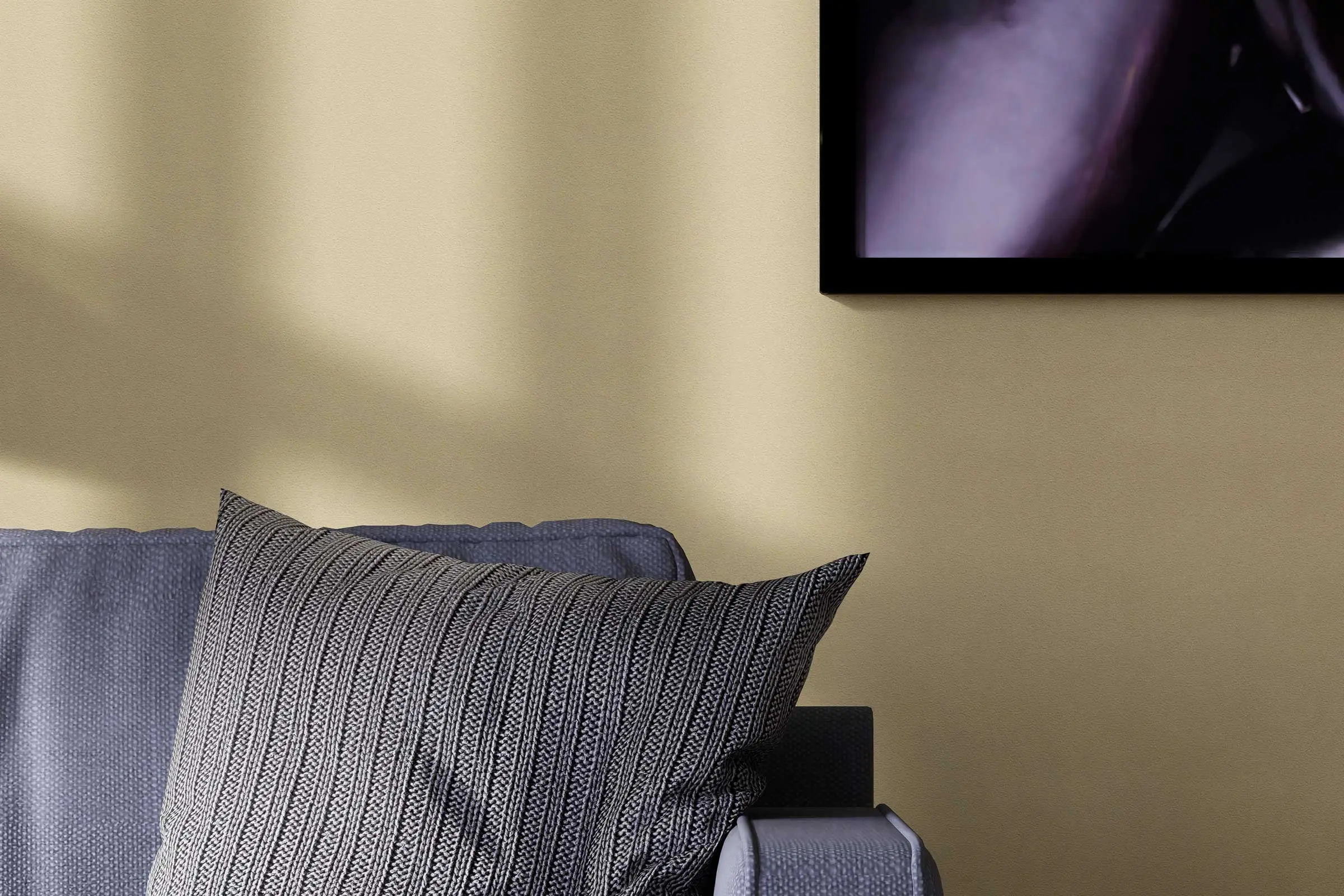 Schlafzimmer-Detail Sessel mit Kissen vor gelber Wand, gestaltet mit den Interior Colors 24+ von Sto