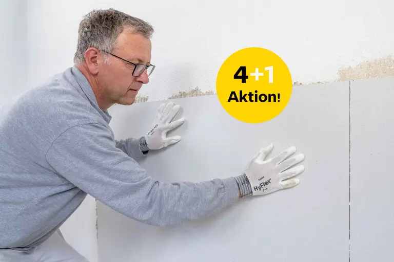 Facharbeiter appliziert Putzträgerplatte an die Wand  