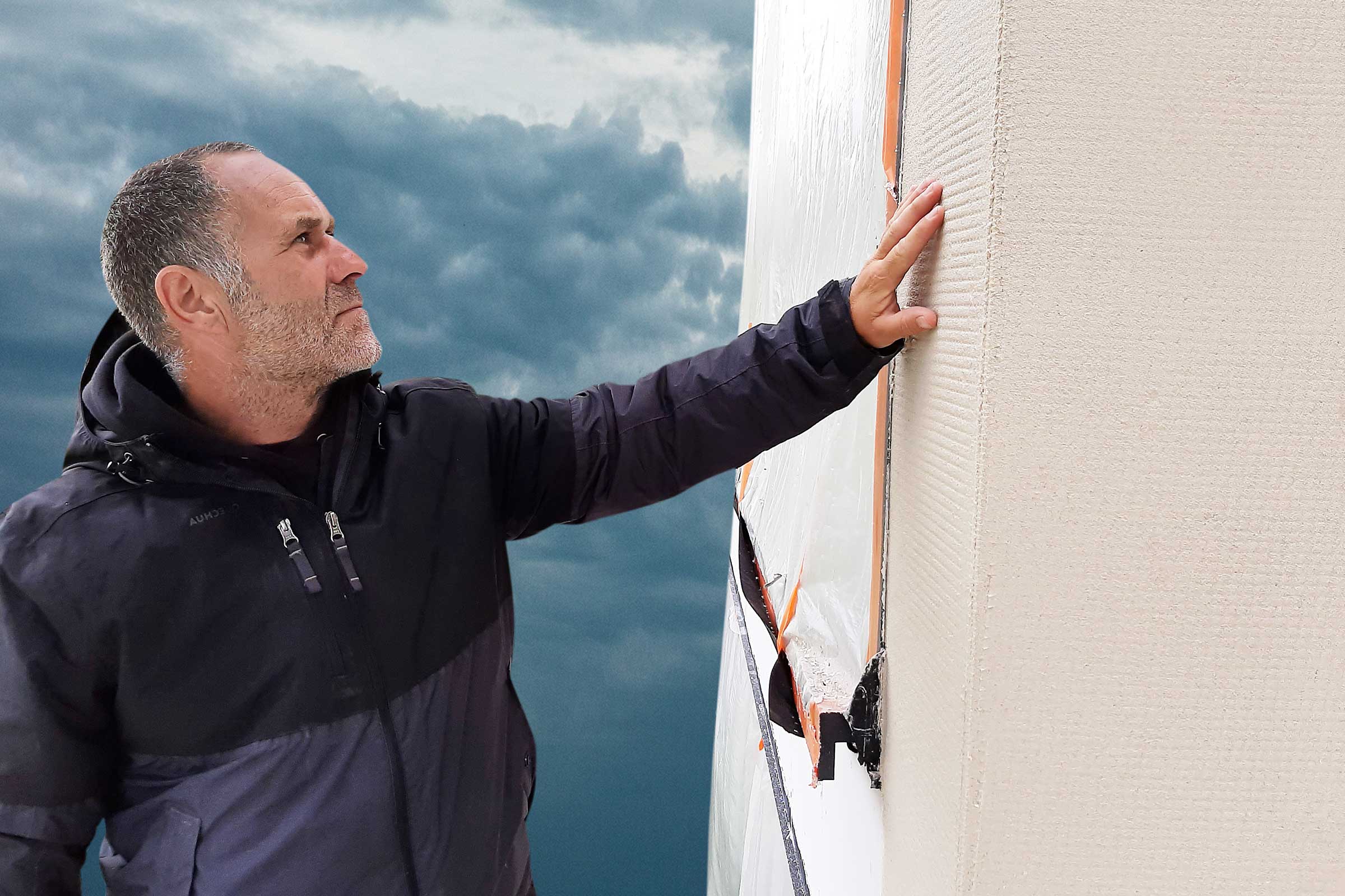 Verarbeiter auf dem Baugerüst prüft die Fassade