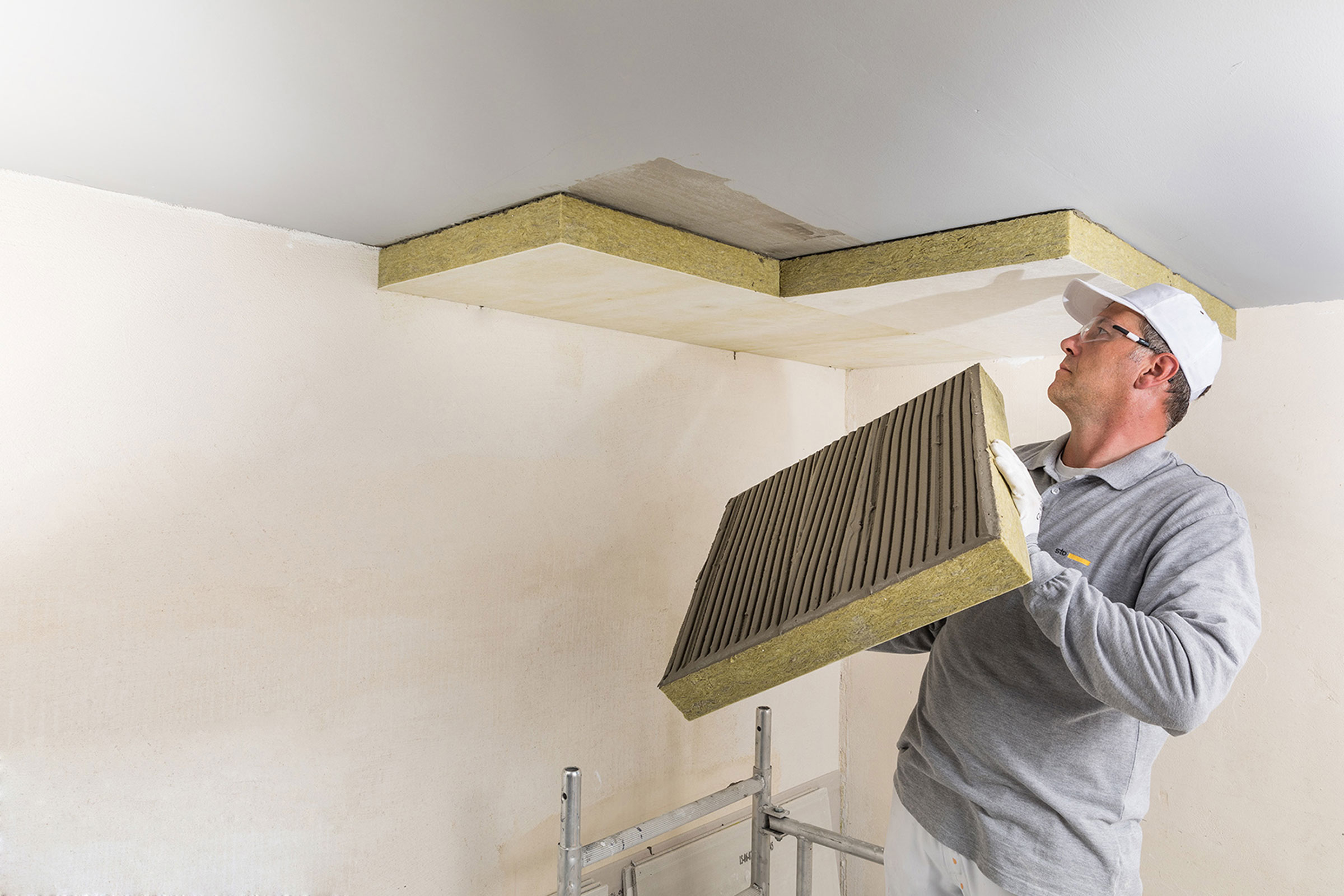 Fachhandwerker klebt eine Dämmplatte an die Decke.