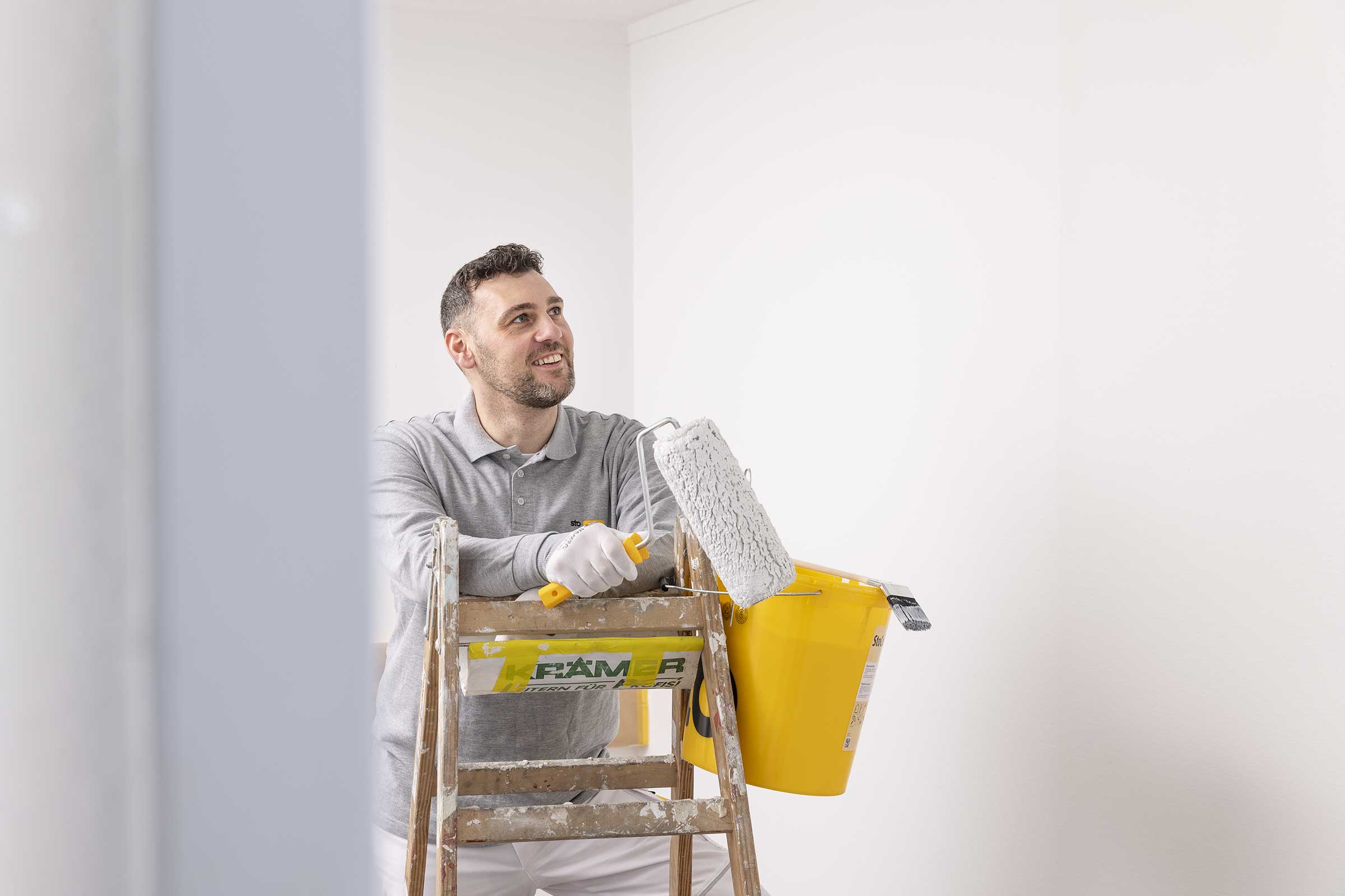 Fachhandwerker mit Eimer StoColor PuraClean an Leiter gelehnt