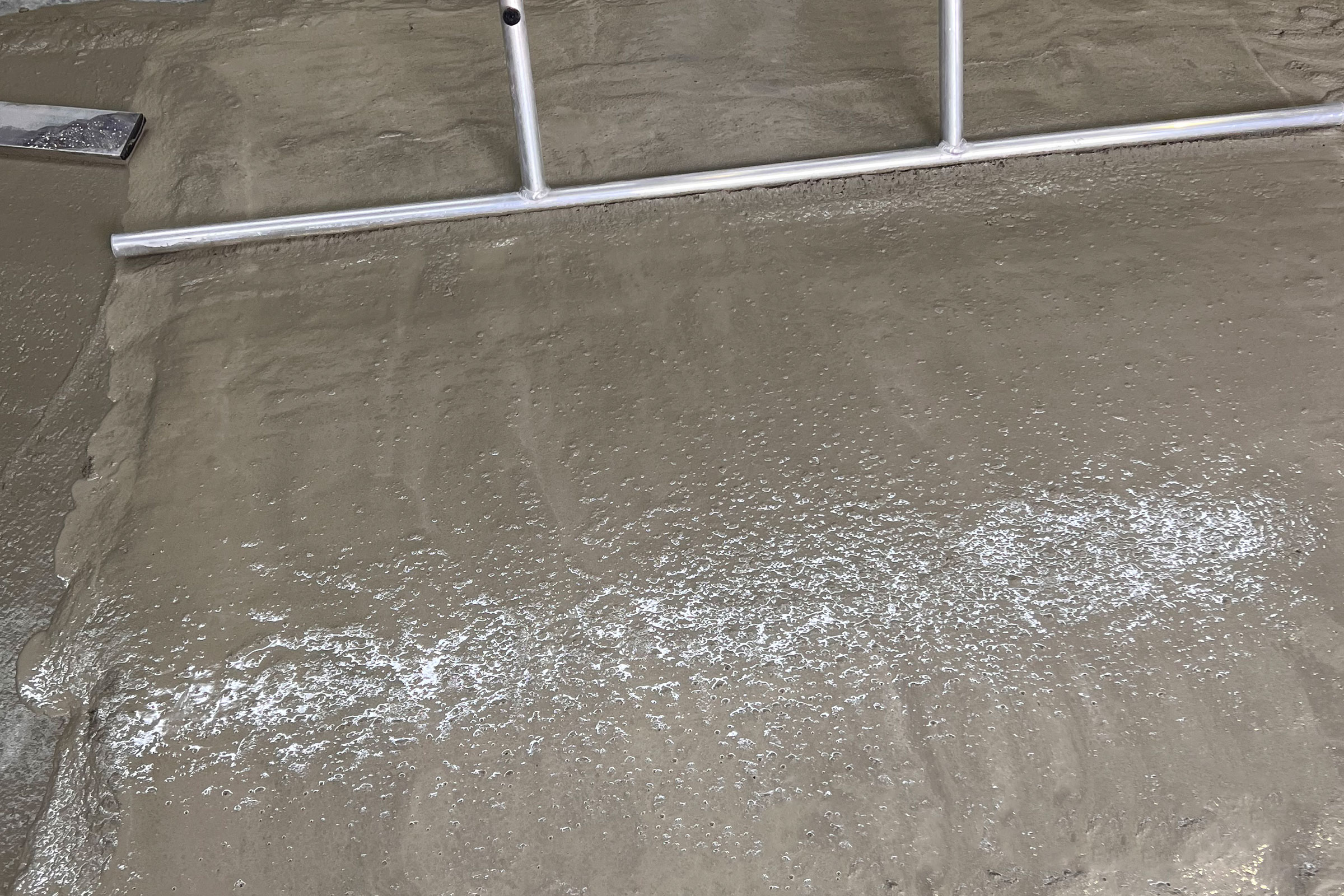 Estrichmörtel wird mit einer Schwbbelstange nivelliert und verdichtet