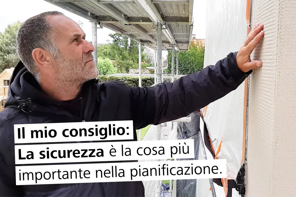 Un artigiano specializzato dipinge una facciata a intonaco. Testo nella foto: prolungamento della st