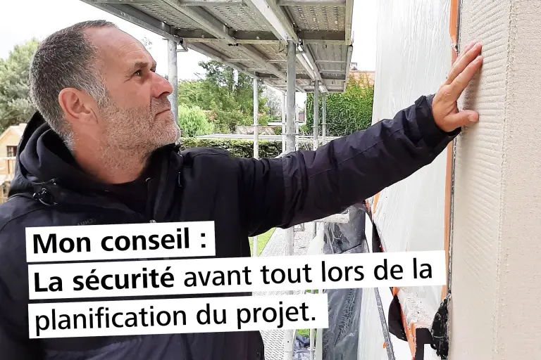 Un ouvrier sur un échafaudage contrôle la surface d'une façade.