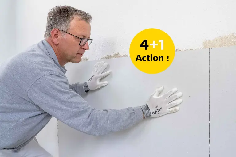 Un ouvrier spécialisé applique un panneau de support d'enduit sur le mur 